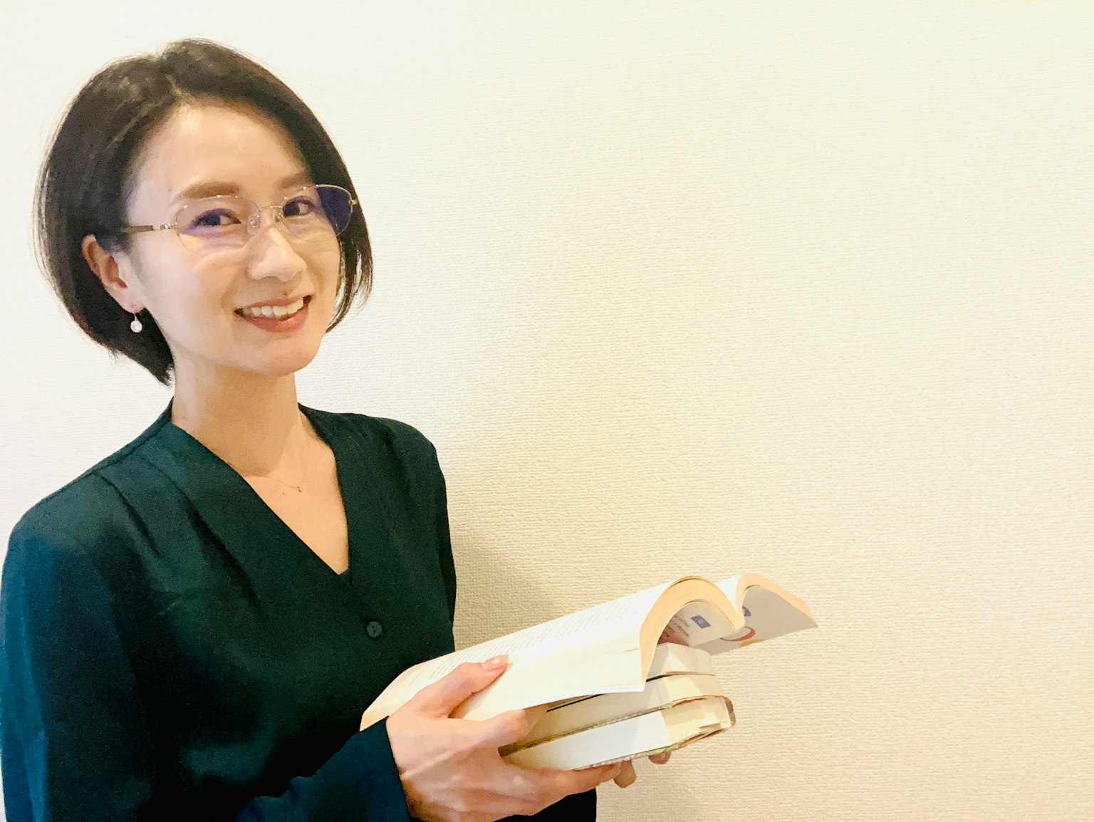Woman smiling while holding books Short hairstyle and simple background