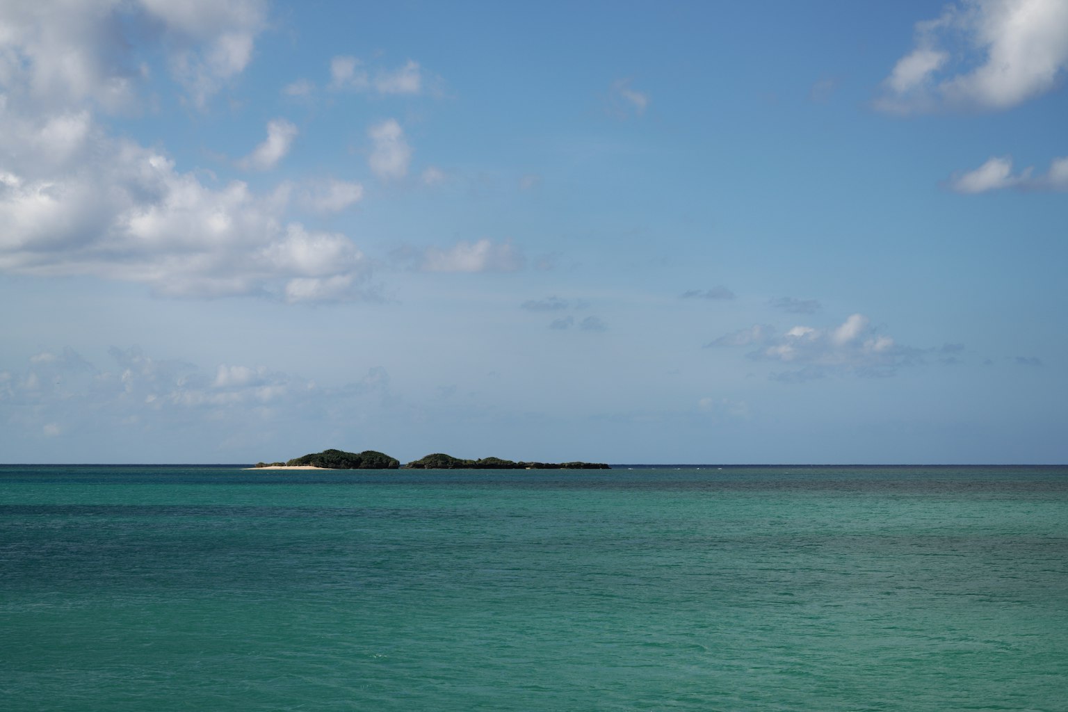 在藍天下，碧綠海水中有一小島的寧靜景色