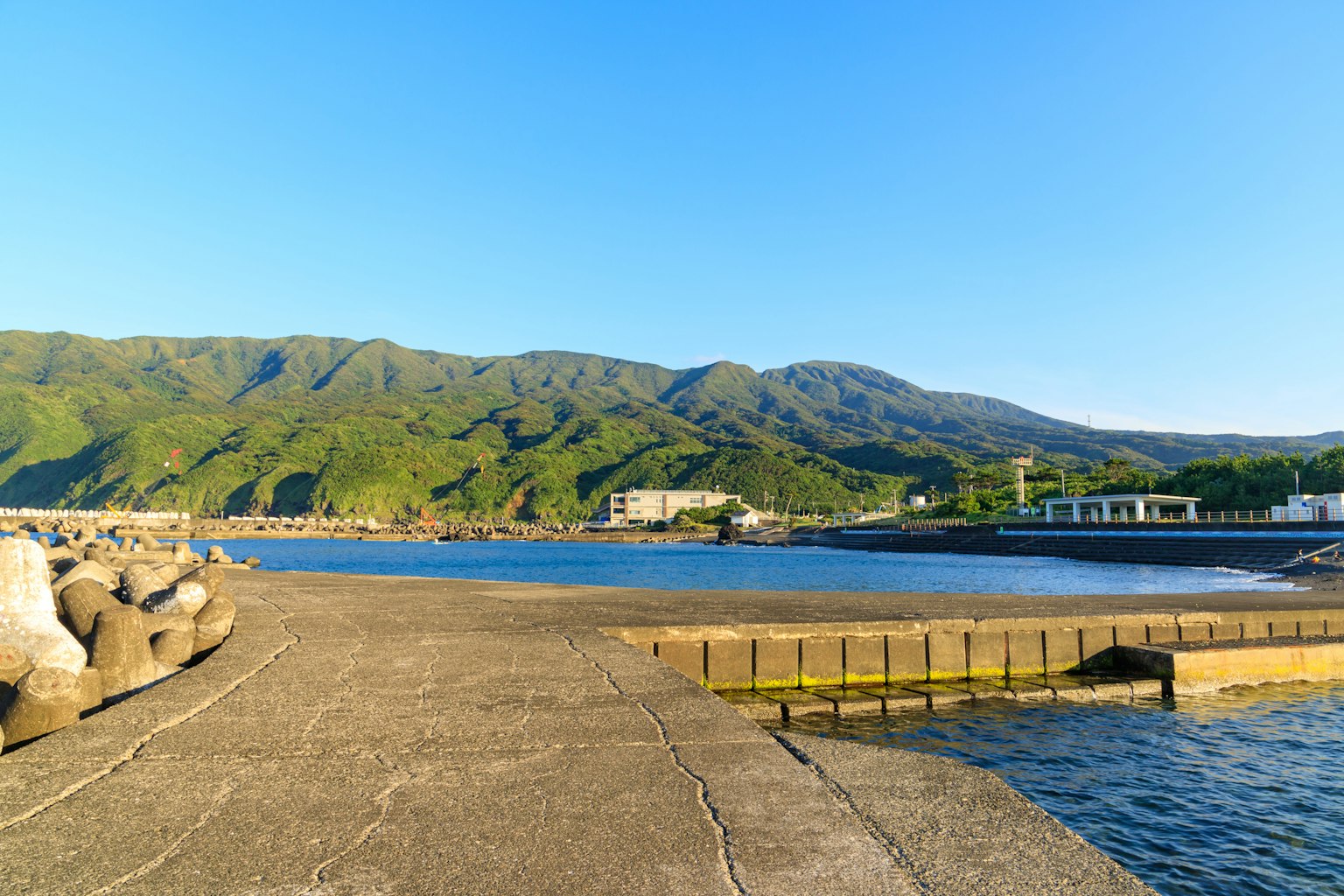 Serene harbor view with calm sea and green mountains