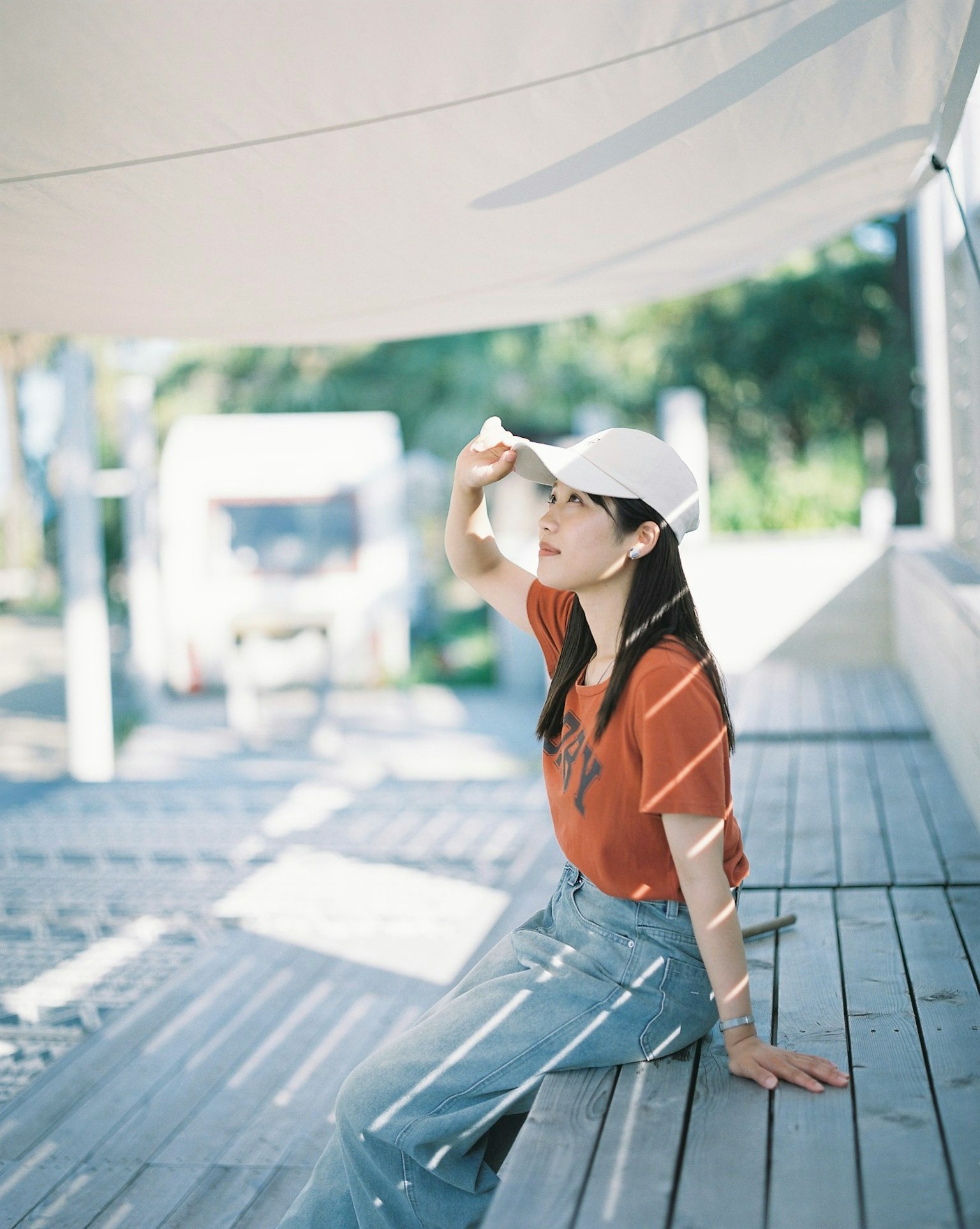 Một người phụ nữ đội mũ ngồi trên hiên gỗ ngoài trời