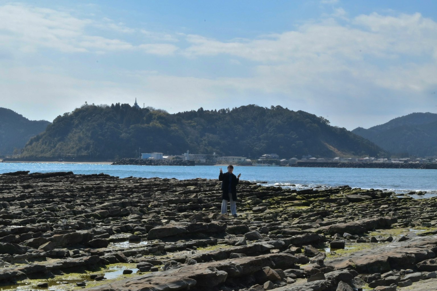 站在岩石海岸上的人和背景的山