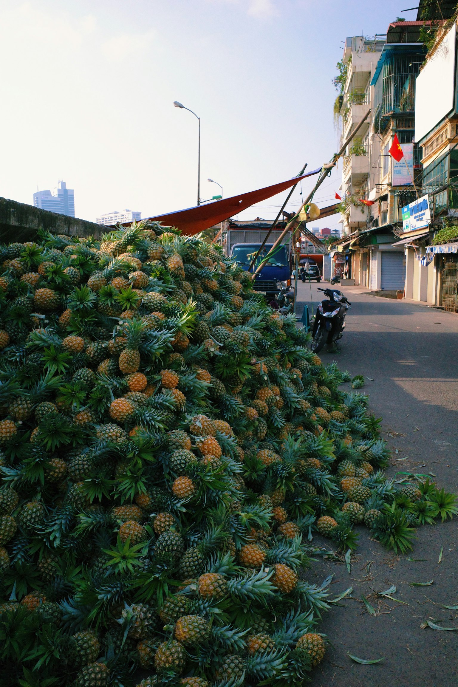 Ein großer Haufen Ananas auf der Straße mit Gebäuden im Hintergrund