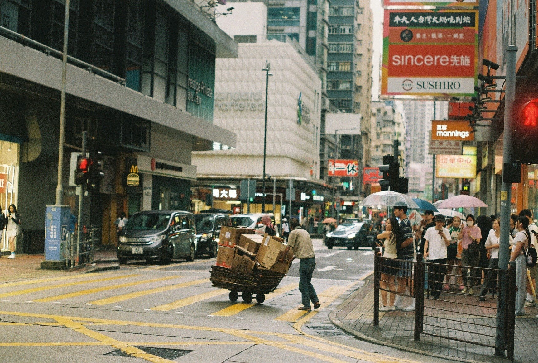 傘をさした人と車が行き交う街の通りの風景