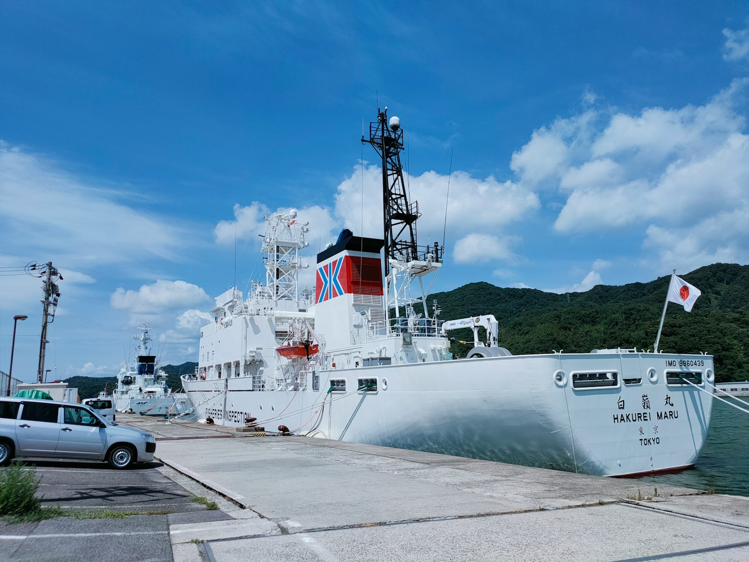 White ship docked at the harbor with blue sky and mountains in the background