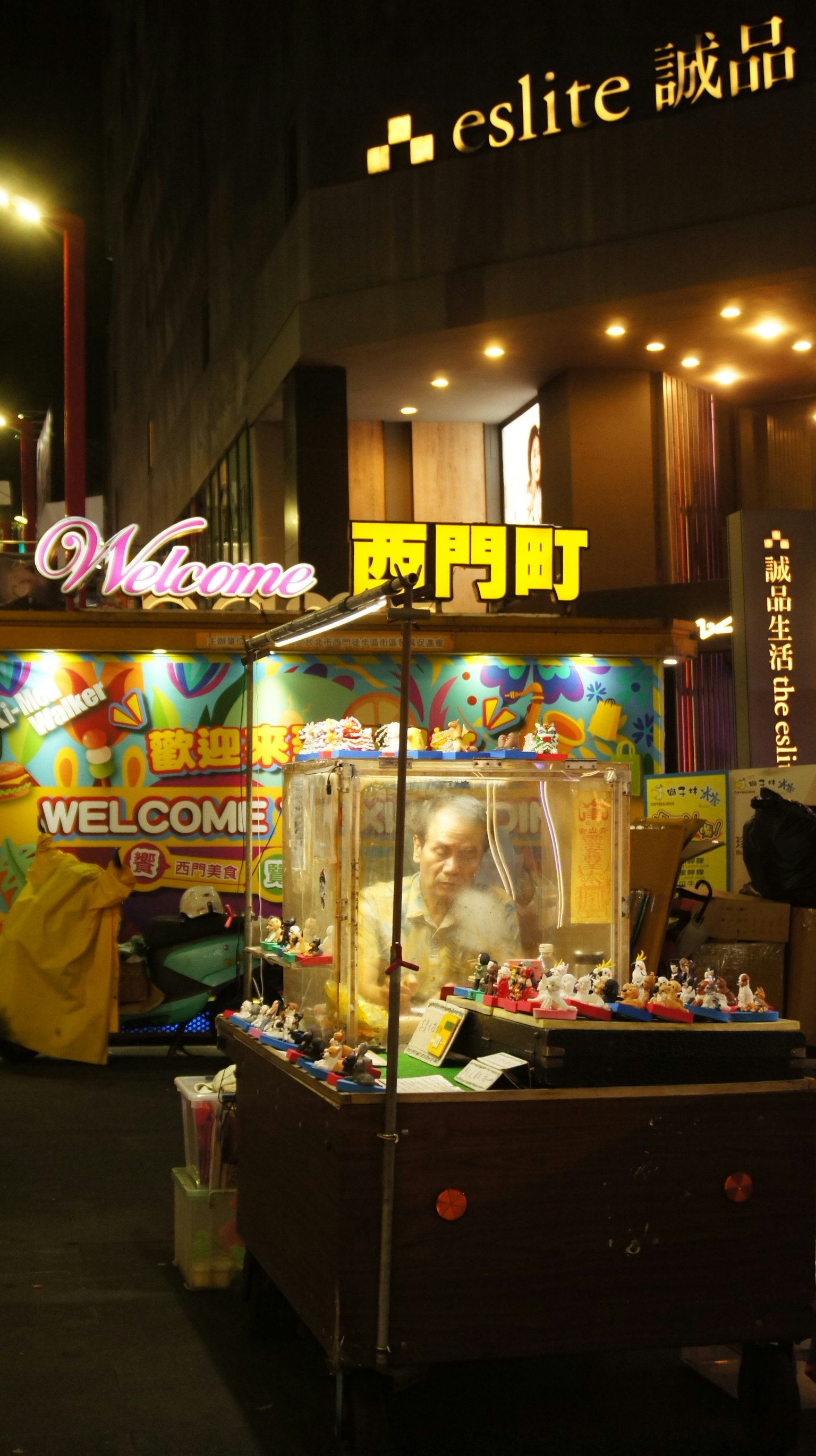 夜の屋台でカラフルな看板と「WELCOME」の文字が見える