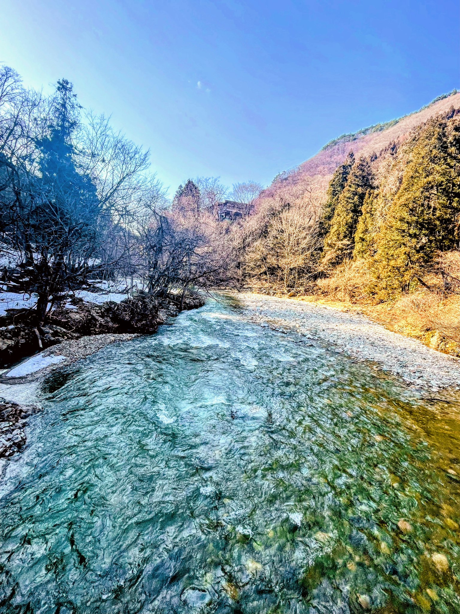 雪殘留的山間河流風景 藍天和樹木環繞