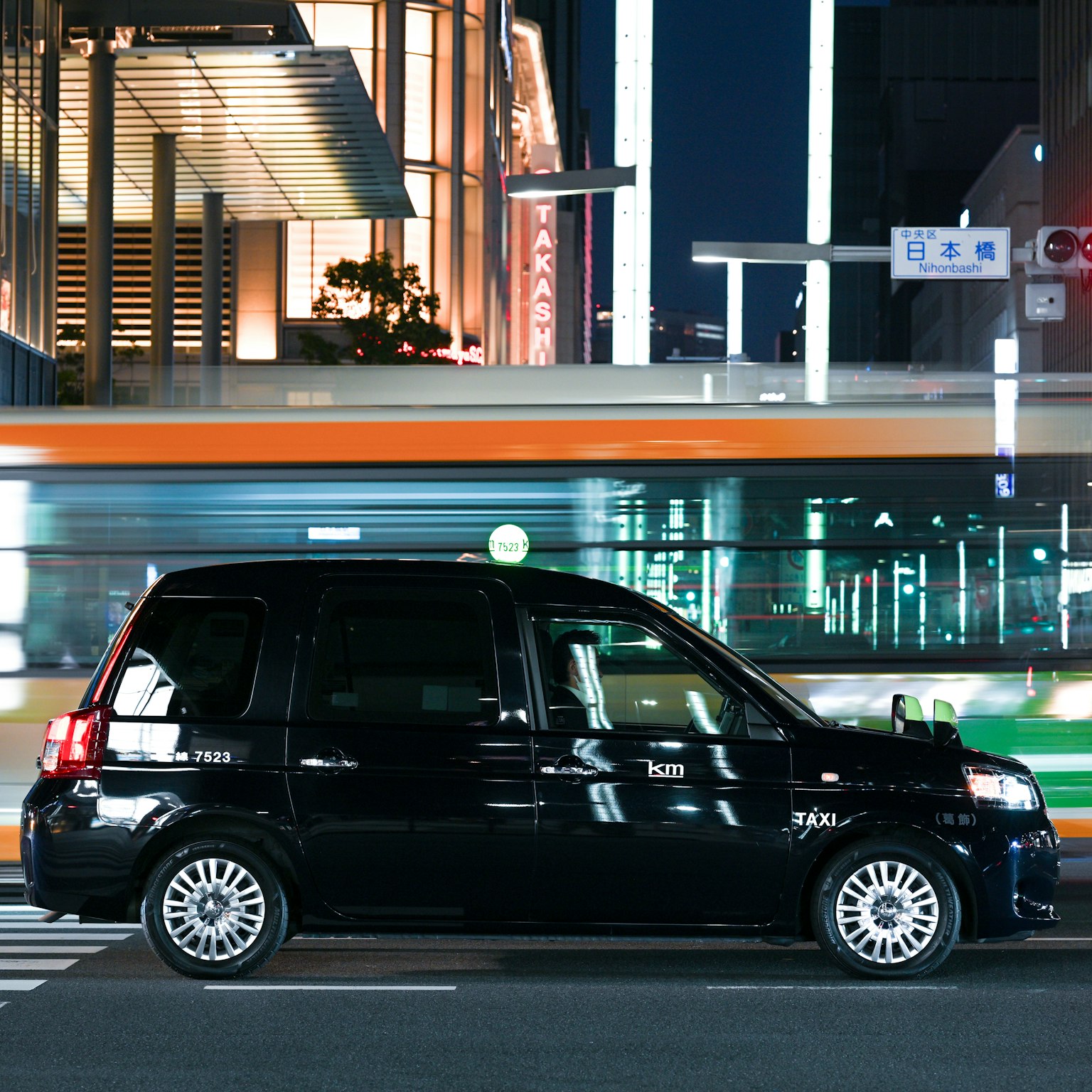 東京街角停著的黑色計程車和模糊的公車燈光