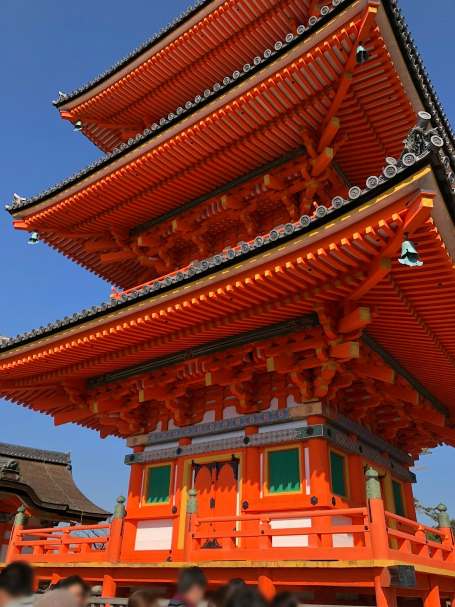 Vibrant orange three-story pagoda stands under a blue sky