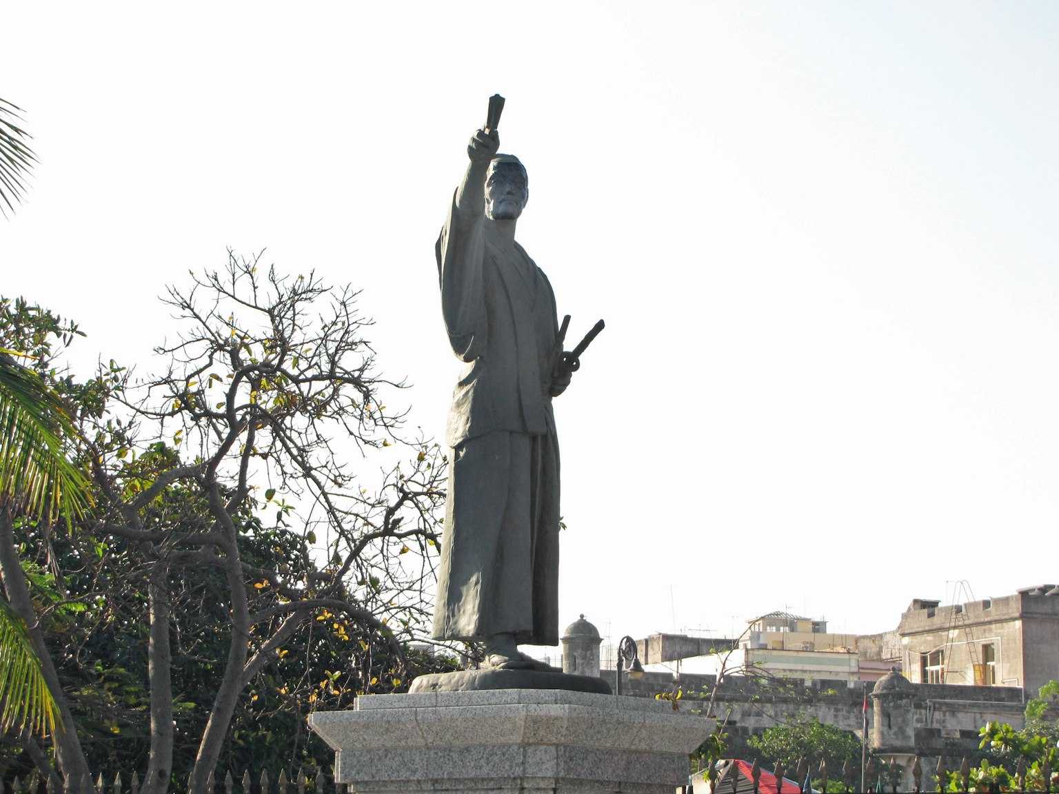 Une statue en bronze d'un guerrier se tenant sur un haut piédestal contre un ciel bleu