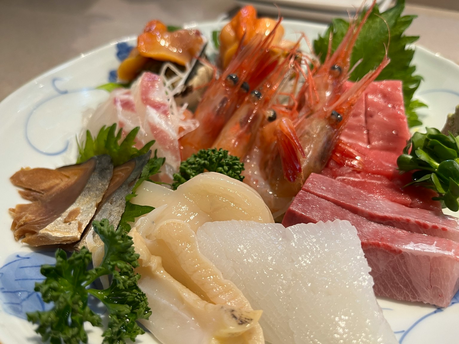Plateau de sashimi frais avec des crevettes, du thon, des coquillages et une garniture de feuilles vertes
