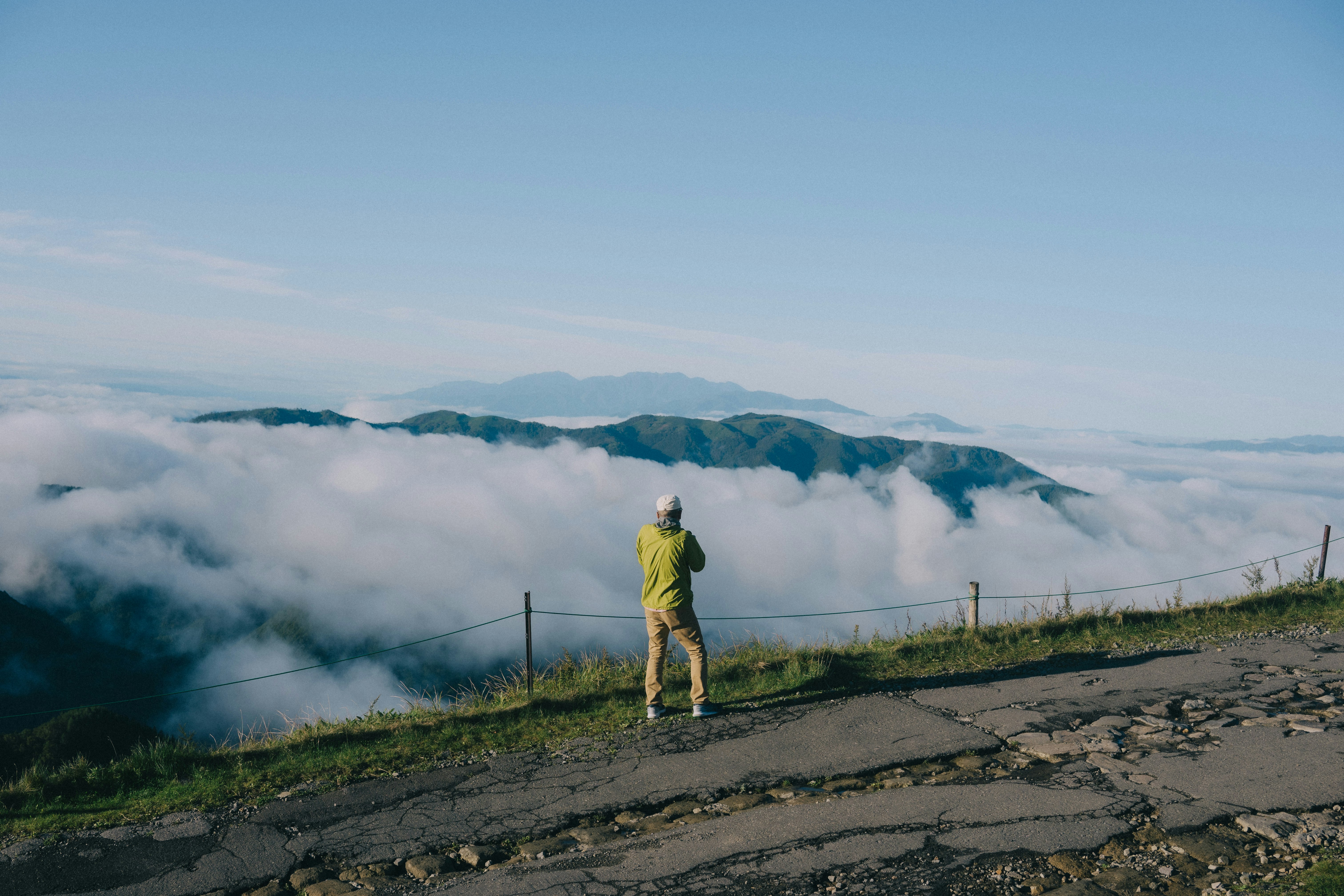 eine Person auf einem Bergrückenweg über dem Meer aus Wolken