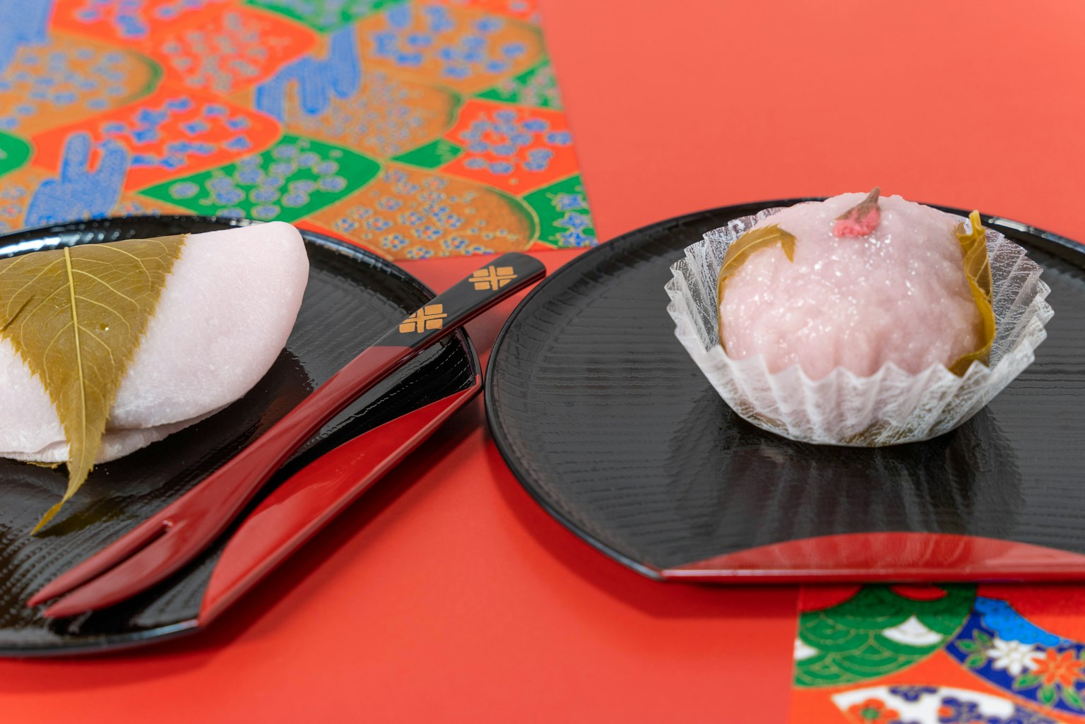 Kue Jepang di atas piring hitam dengan kertas washi berwarna di latar belakang