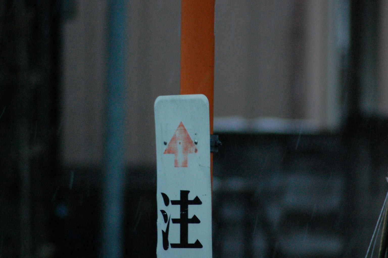 Ein Warnschild mit einem Pfeil, montiert auf einem orangefarbenen Pfahl