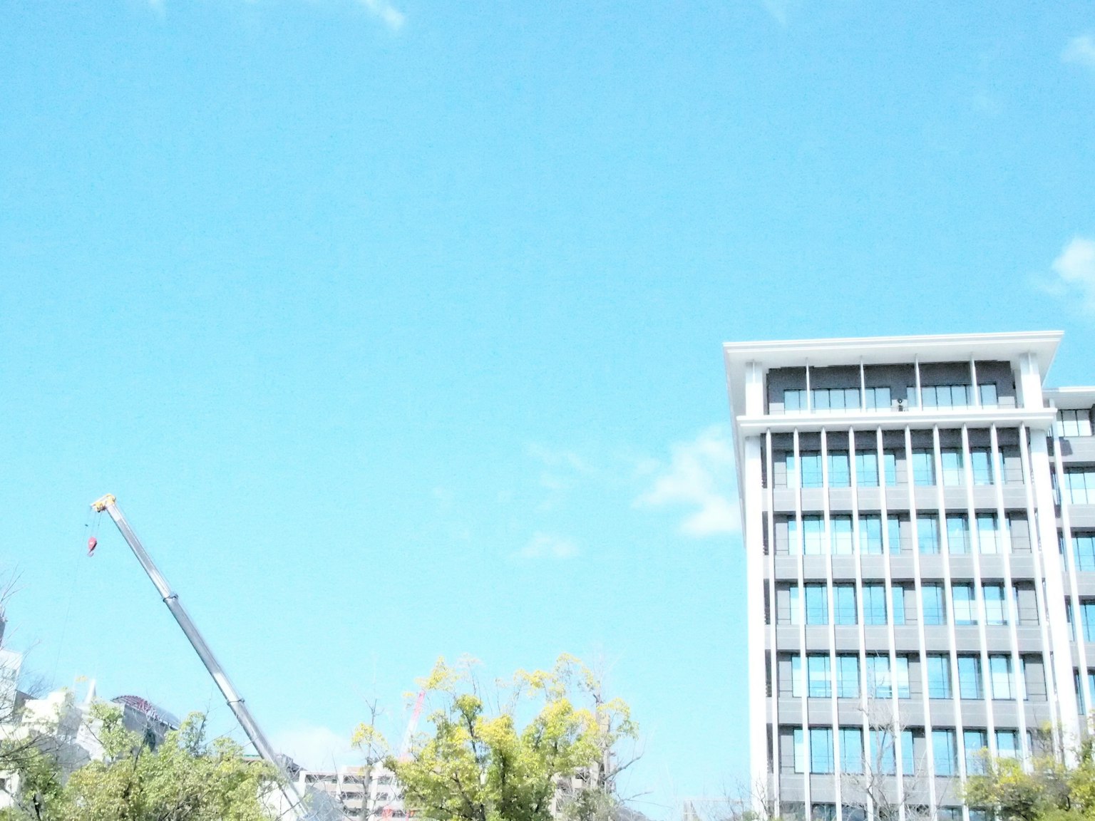 Modern building under a clear blue sky with a crane