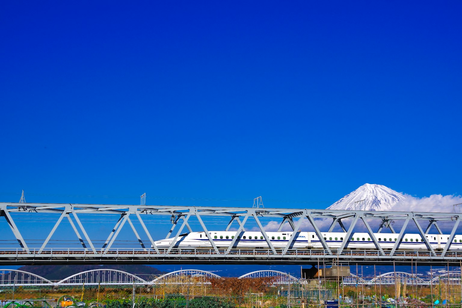 ทิวทัศน์ที่สวยงามมีภูเขาฟูจิและสะพานชินคันเซนใต้ท้องฟ้าสีฟ้า