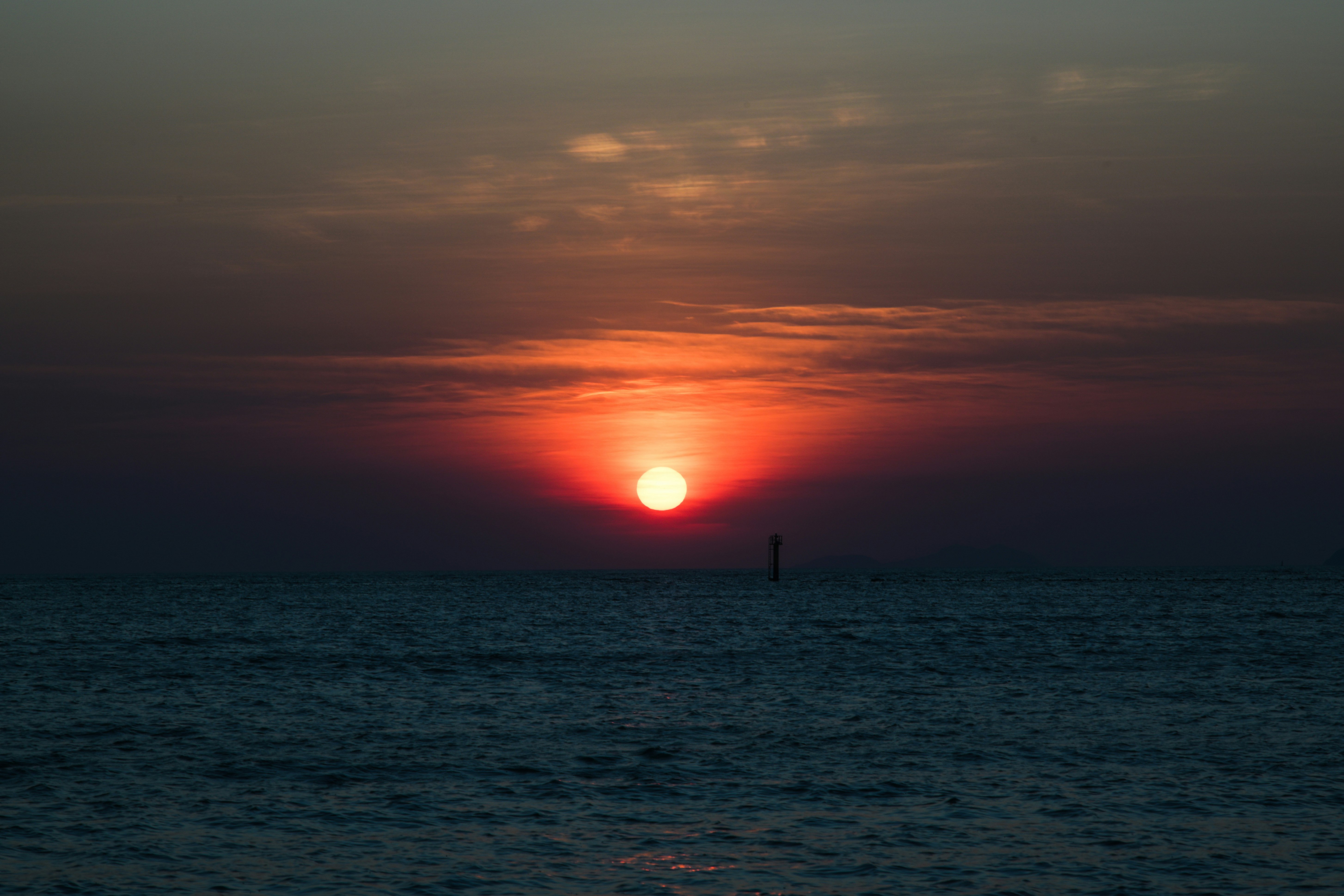 水平線上に沈む夕日と海面の静けさ