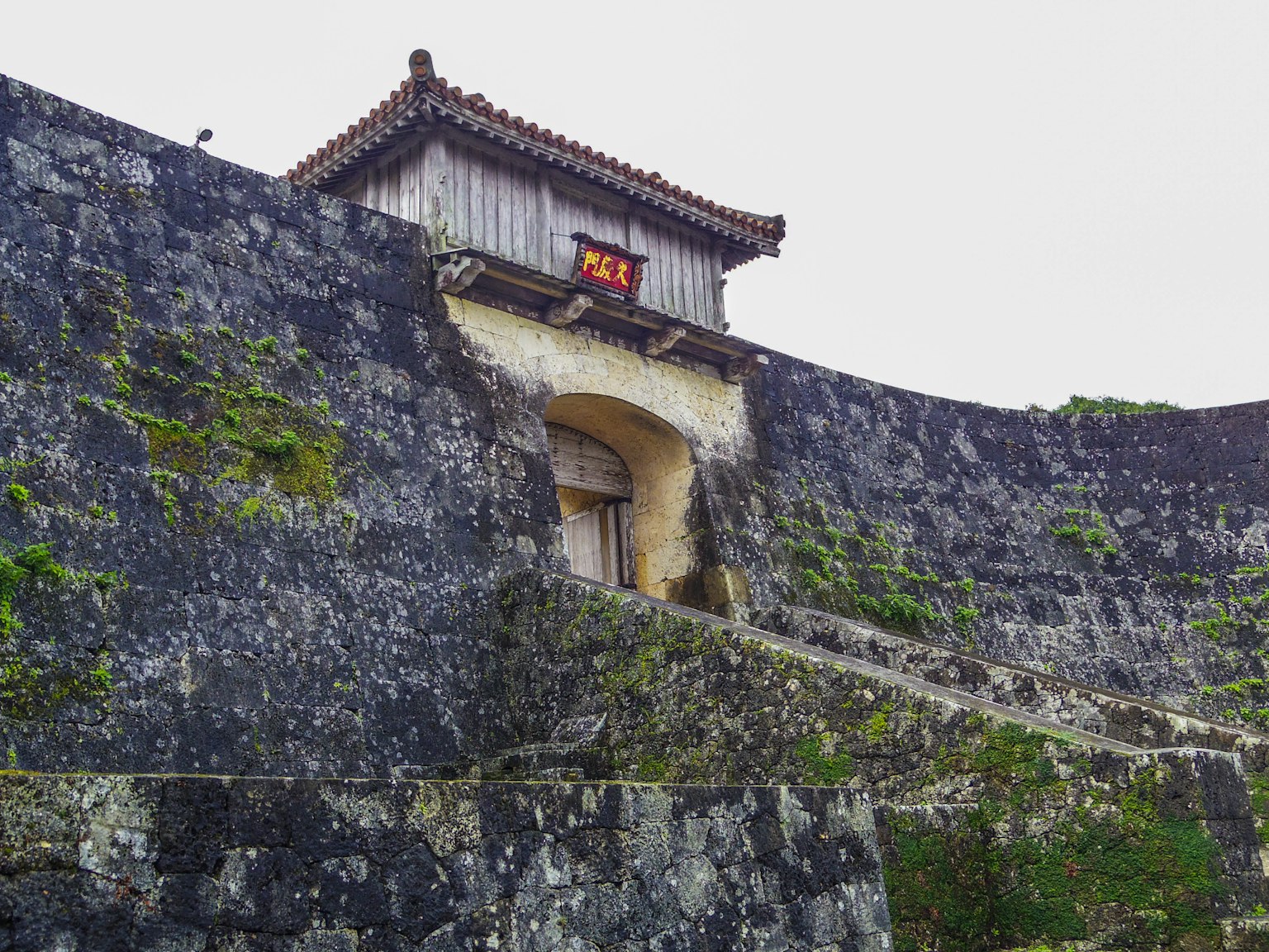 Imagen de un muro de piedra histórico y una puerta en Okinawa