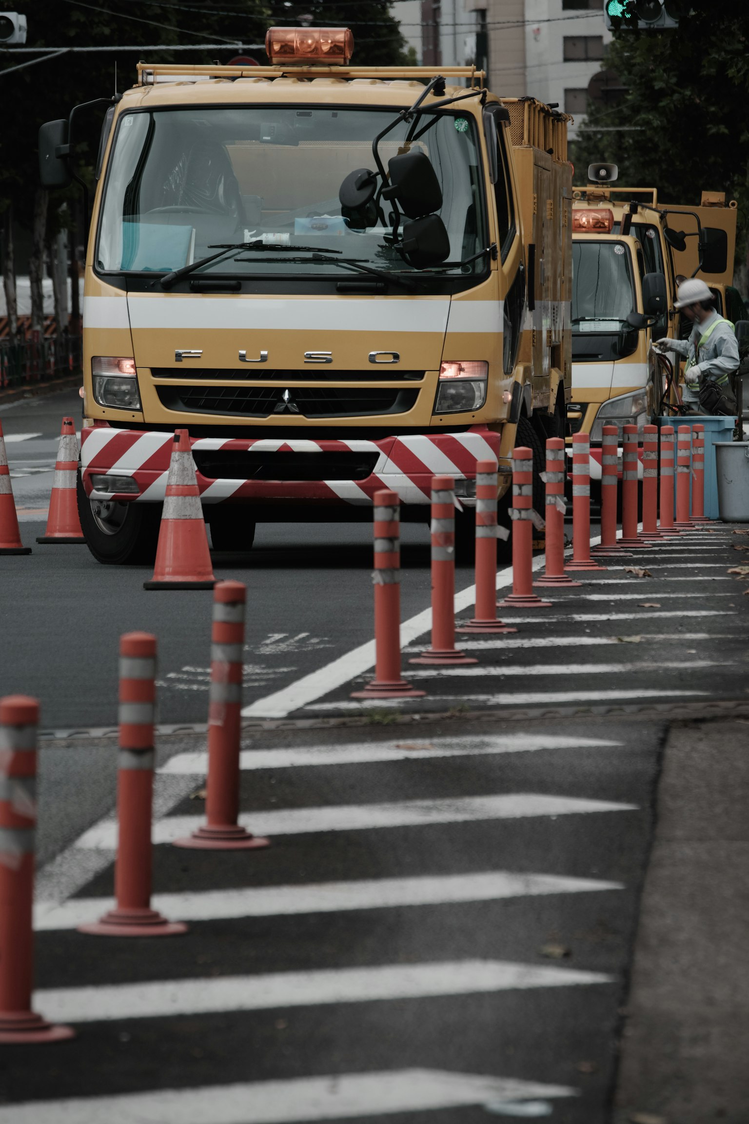 Veicoli gialli da costruzione che lavorano su una strada con coni stradali e segnaletica