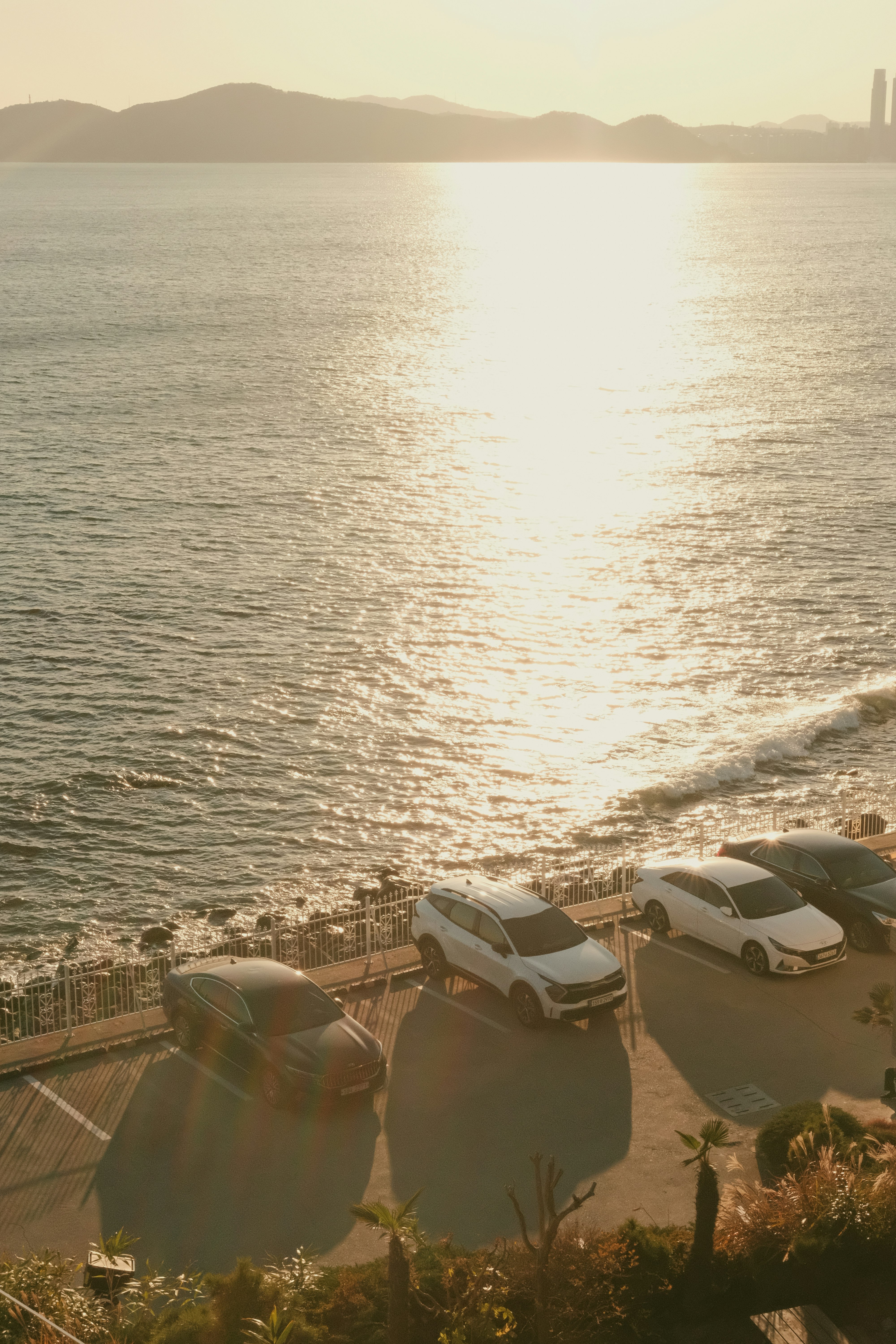 夕日に照らされた海辺の駐車場と波
