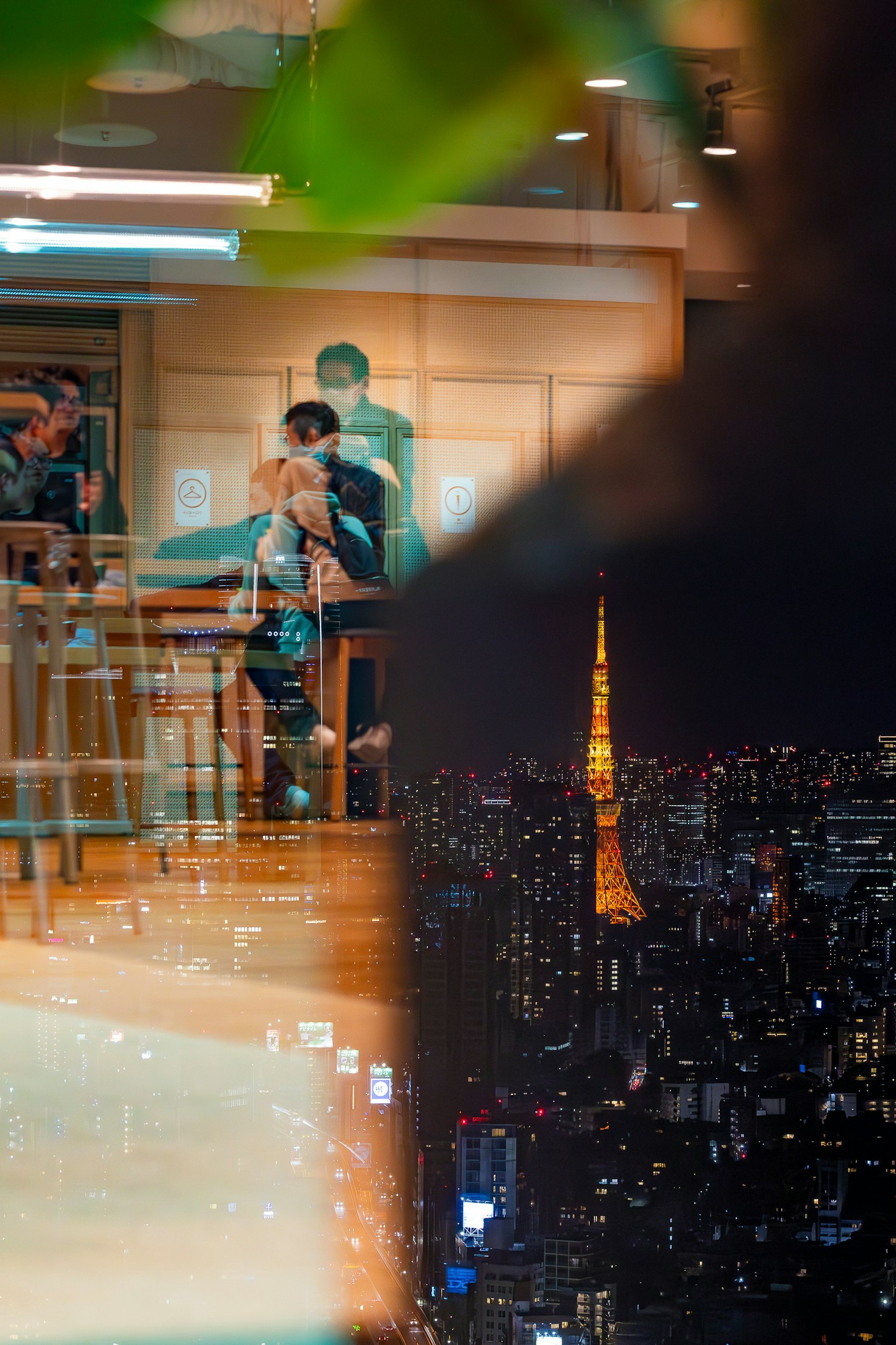 Interno di un caffè con persone riunite e la Torre di Tokyo visibile all'esterno