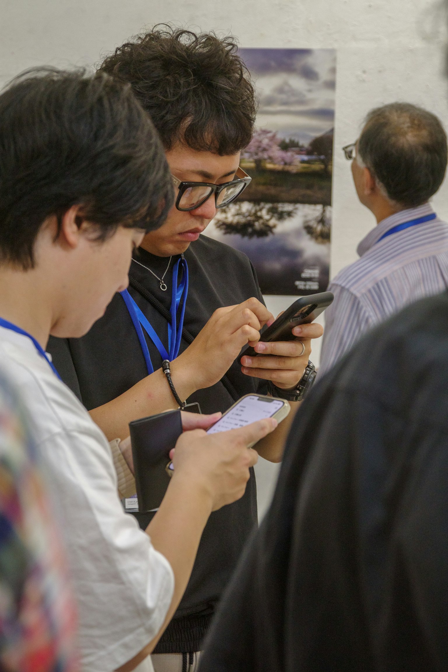 Hai người trẻ tuổi đang sử dụng điện thoại thông minh với một bức ảnh phong cảnh ở phía sau