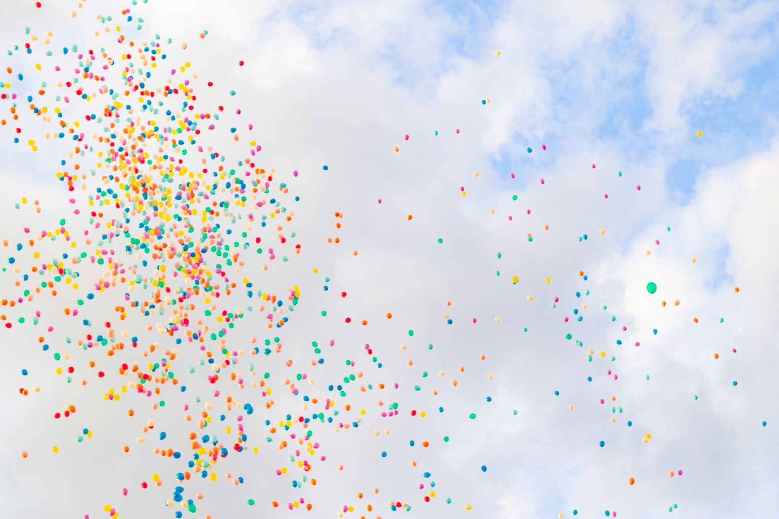Langit dipenuhi balon berwarna-warni mengapung di latar belakang biru