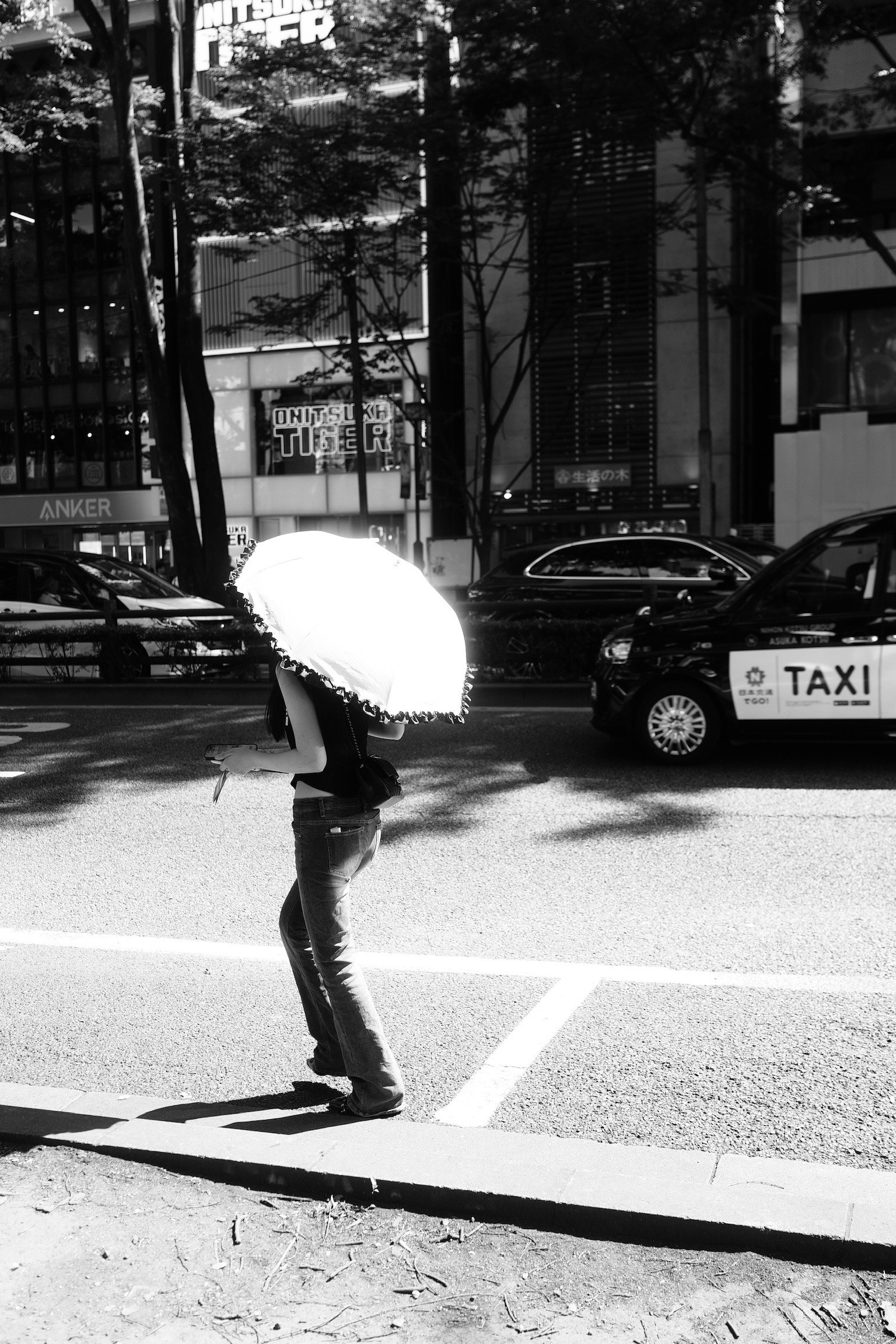 Una persona che attraversa la strada con un ombrello bianco in una scena urbana in bianco e nero