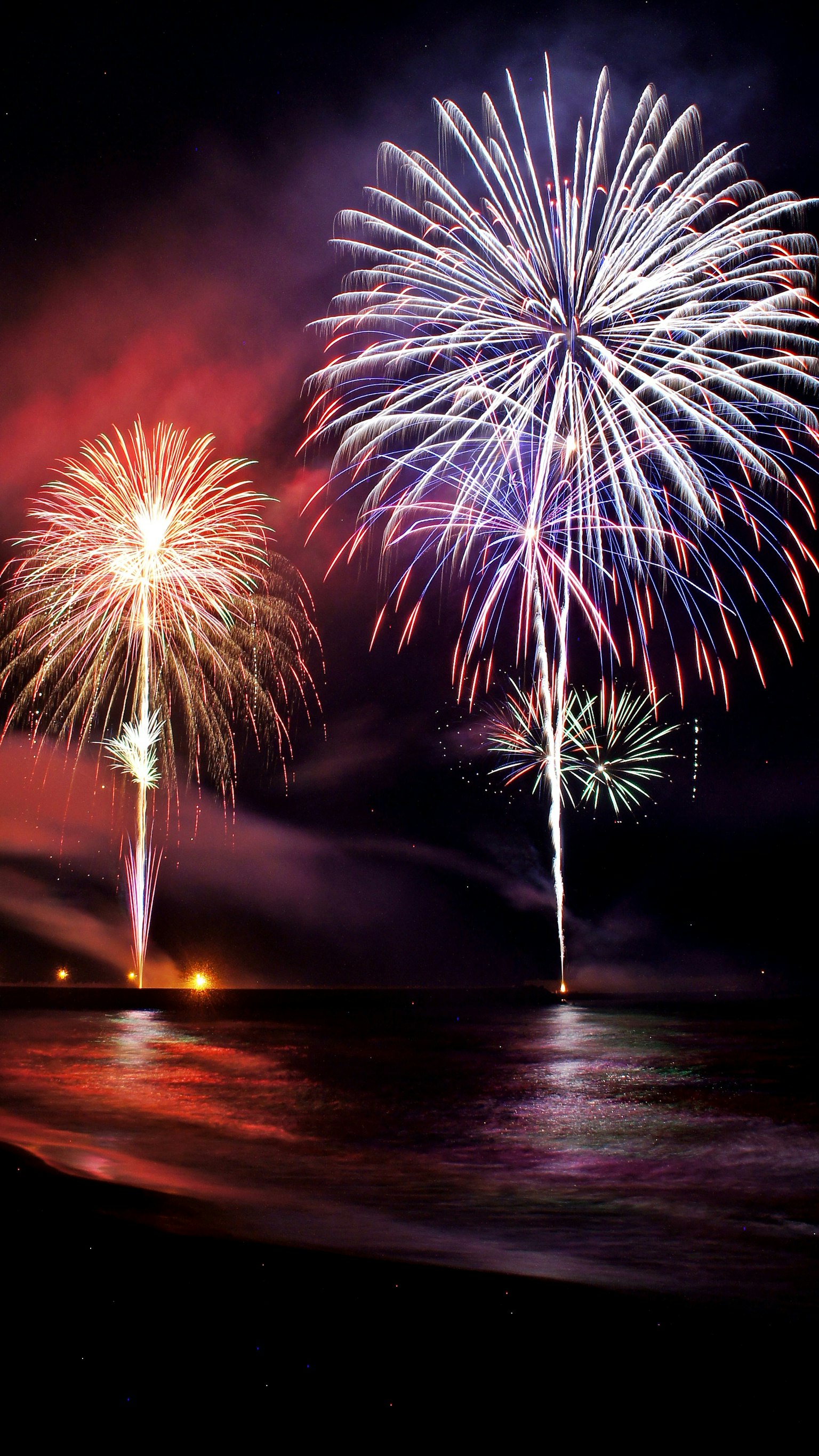 Magnifica esposizione di fuochi d'artificio nel cielo notturno riflessi sul mare e gradiente di colori