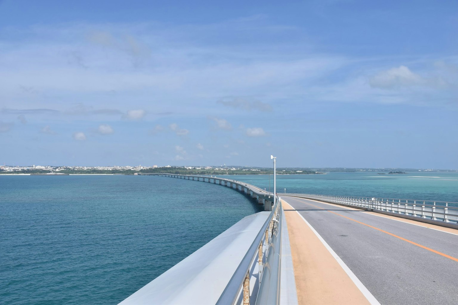Curved bridge over blue sea with clear sky