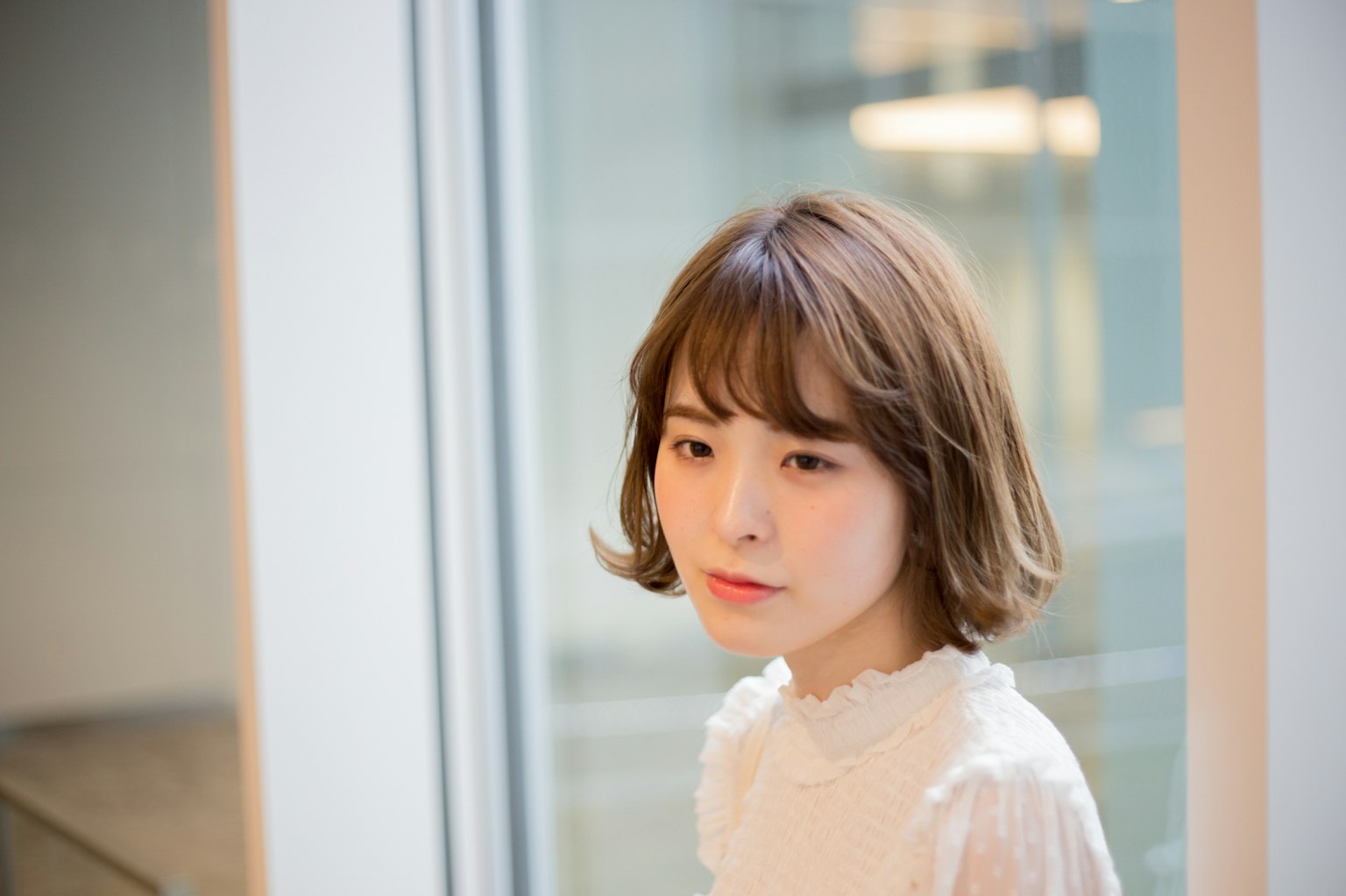 靠近窗户的女性肖像 明亮的头发和白色衬衫