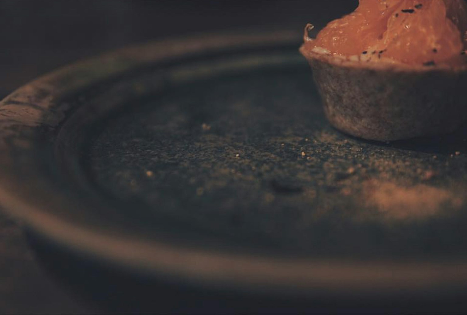 Un primer plano de un postre en un plato con un fondo oscuro