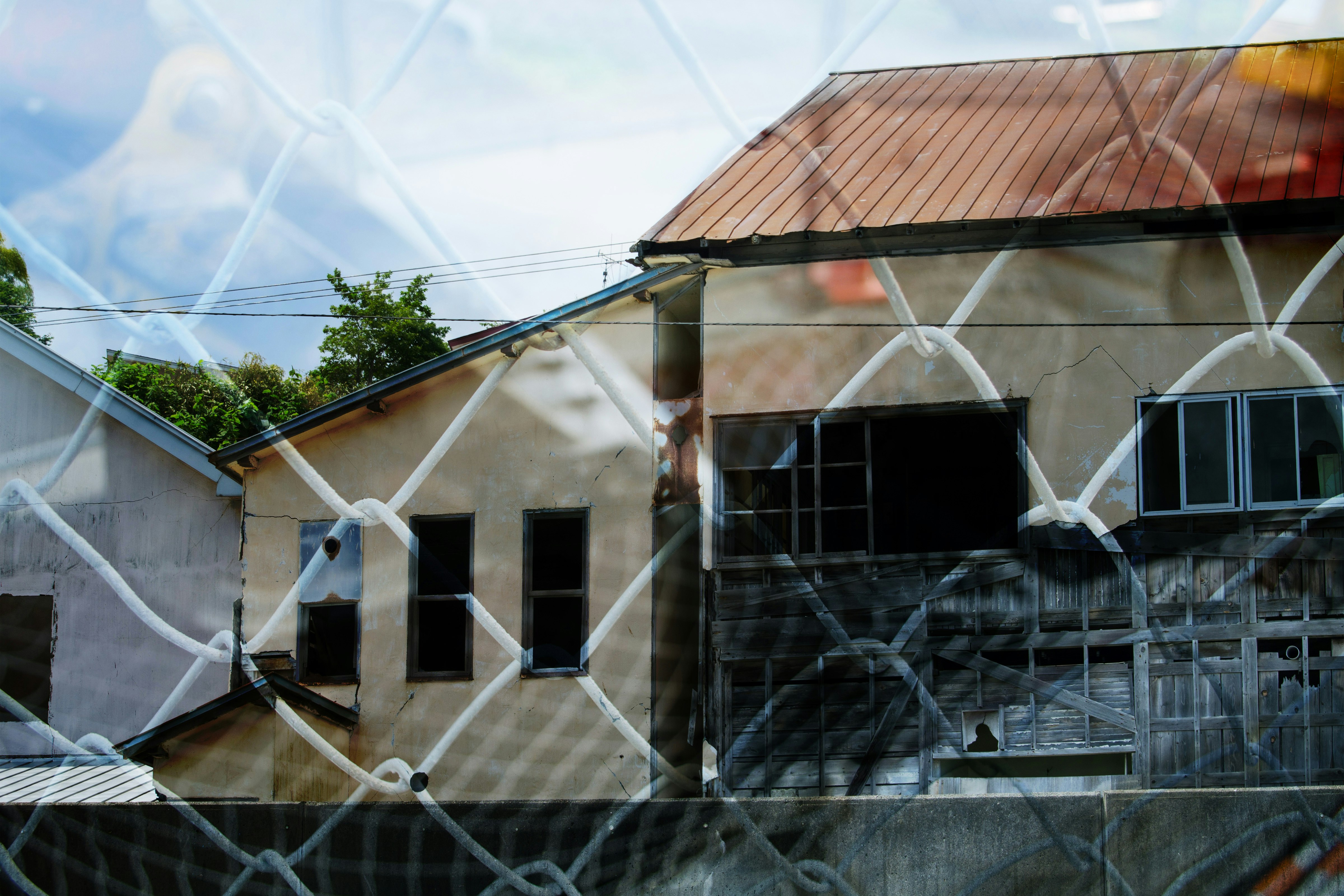 鐵絲網圍欄後的老建築與庭院