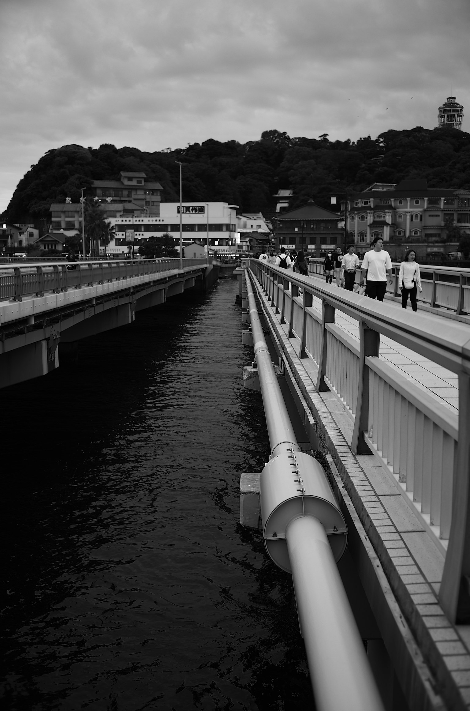 Immagine in bianco e nero di un ponte lungo un canale con persone che camminano