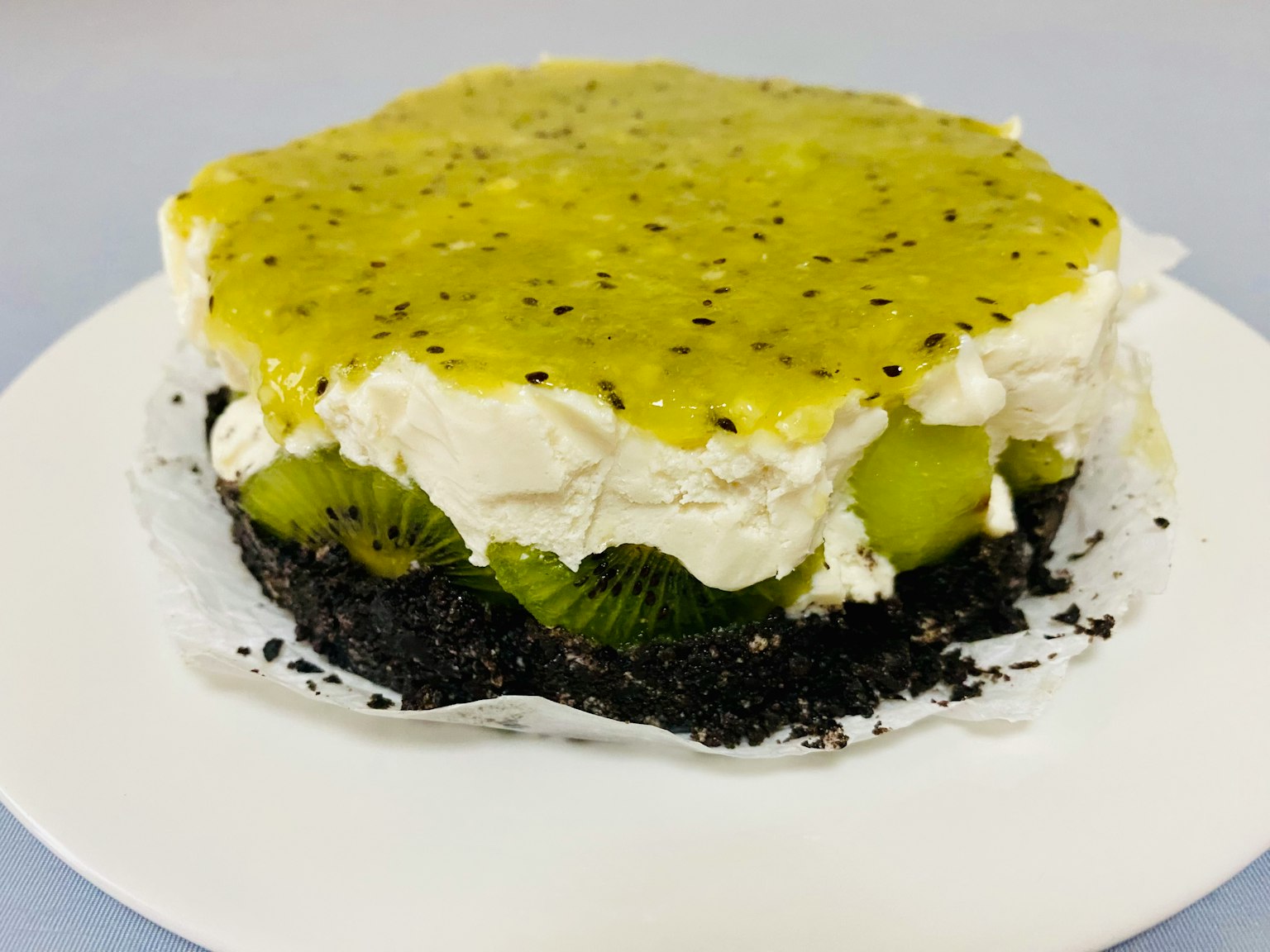 Gâteau en couches avec de la crème et des fruits sur une croûte de biscuit noir