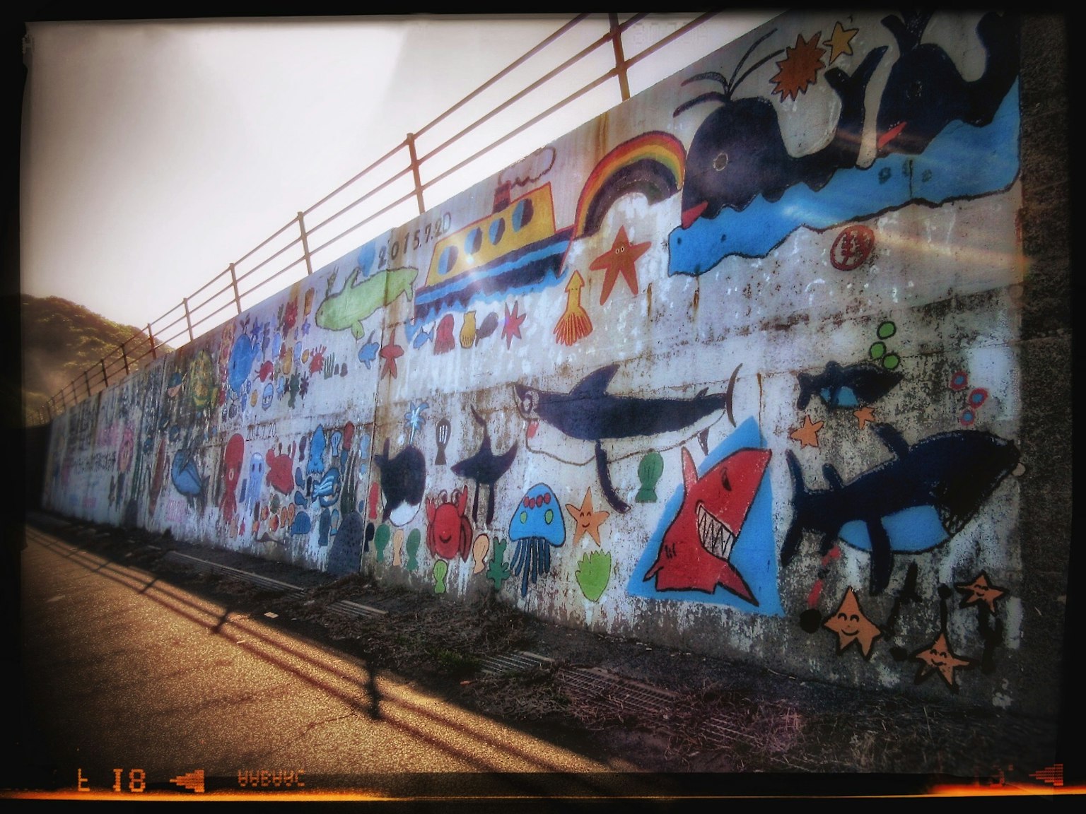 Mural berwarna-warni yang menampilkan kehidupan laut dan pemandangan di dinding beton