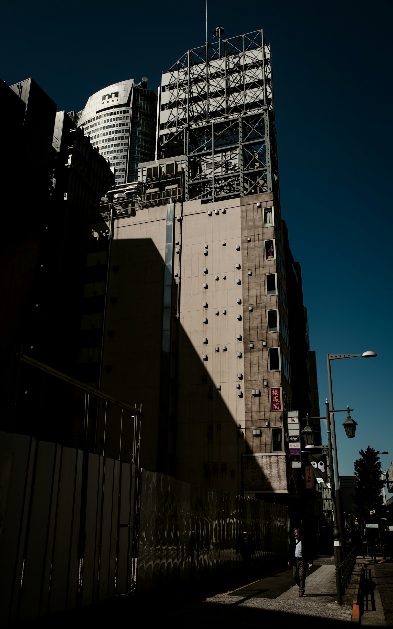 Escena urbana con un edificio alto proyectando una sombra contra un cielo azul claro