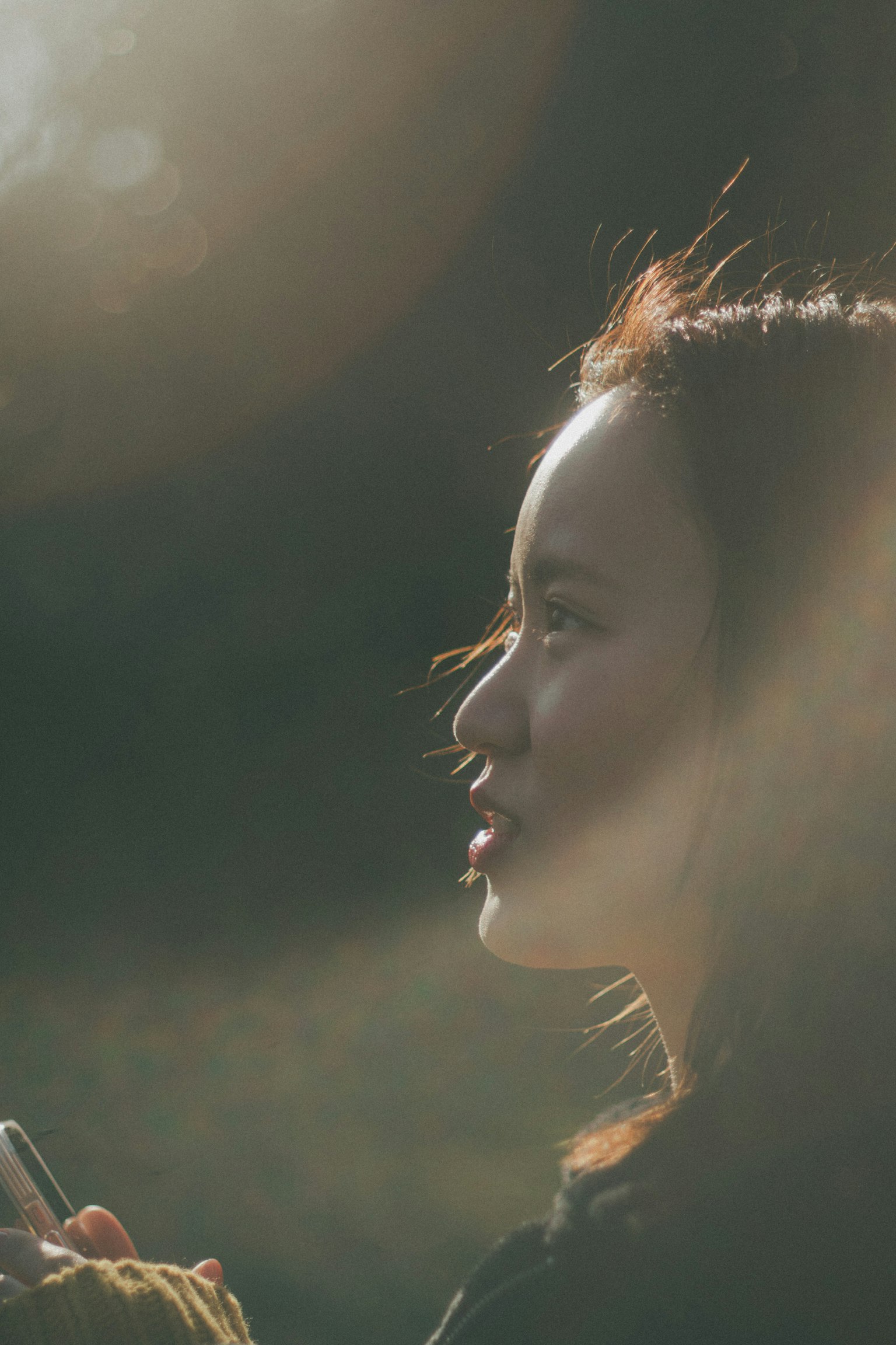 Une femme tenant un smartphone avec son profil illuminé par une douce lumière