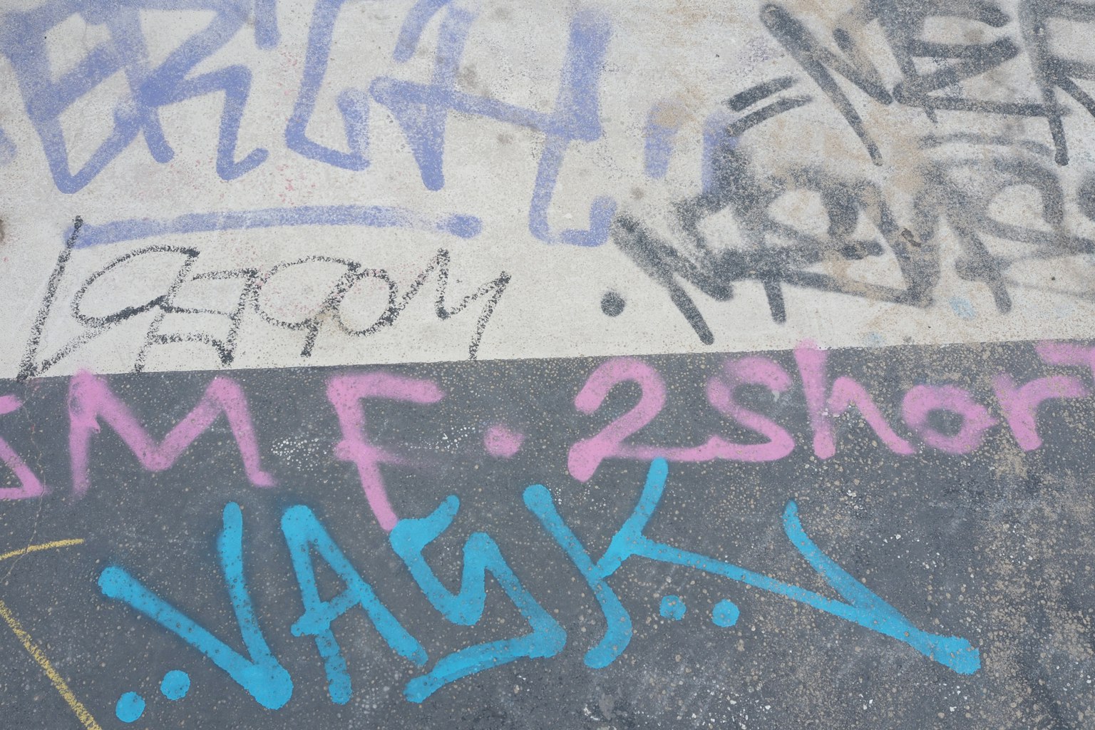 Colorful graffiti on pavement featuring various styles of lettering