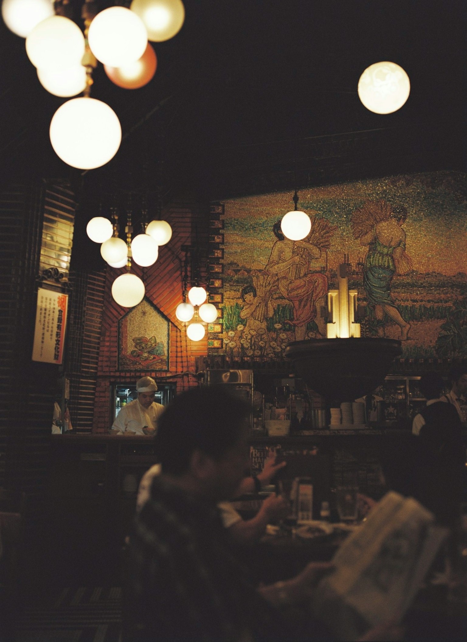 Dunkel beleuchtetes Café-Interieur mit runden Lichtern und einem Wandgemälde