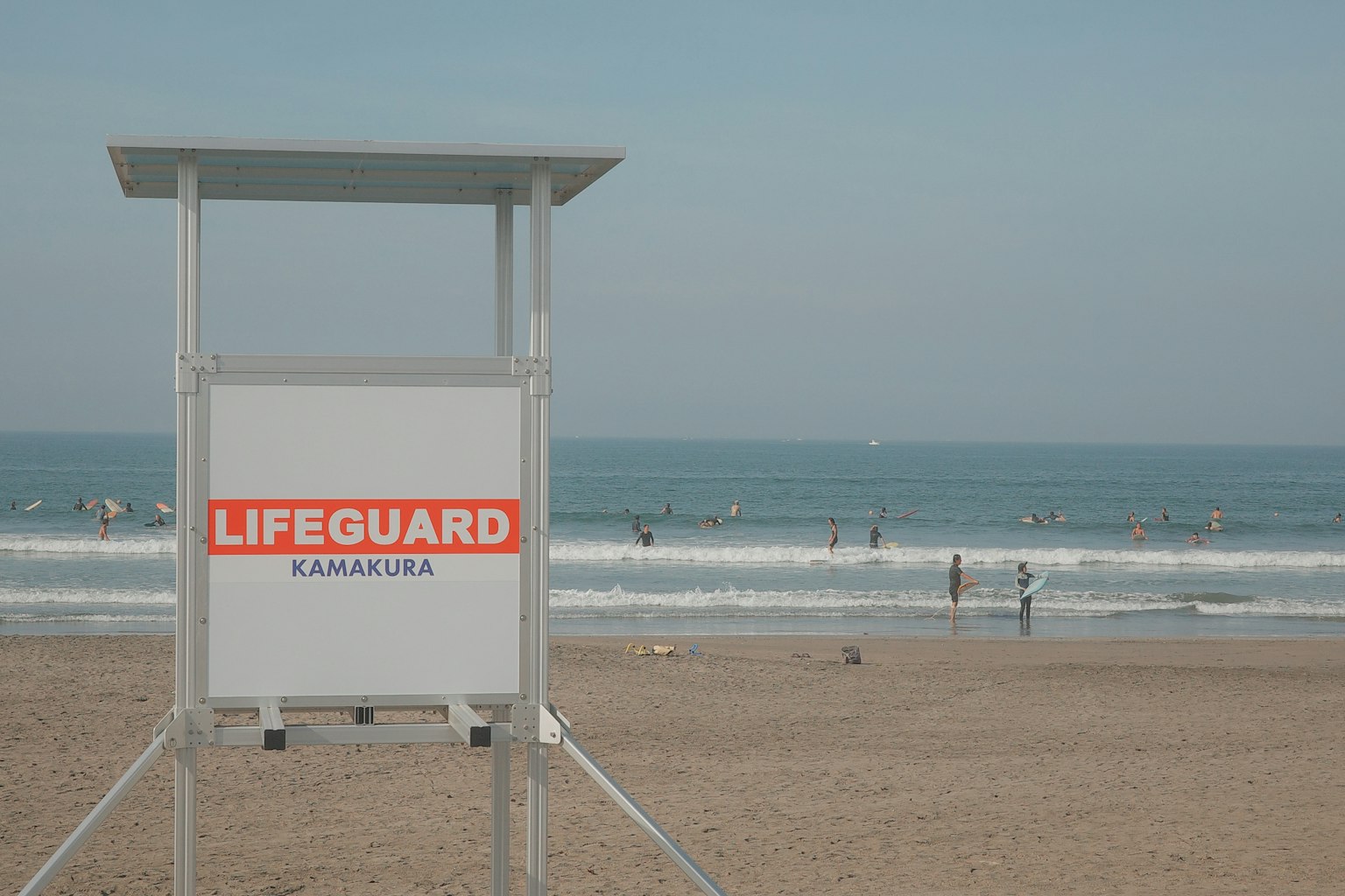 Lifeguard tower on the beach with waves and surfers