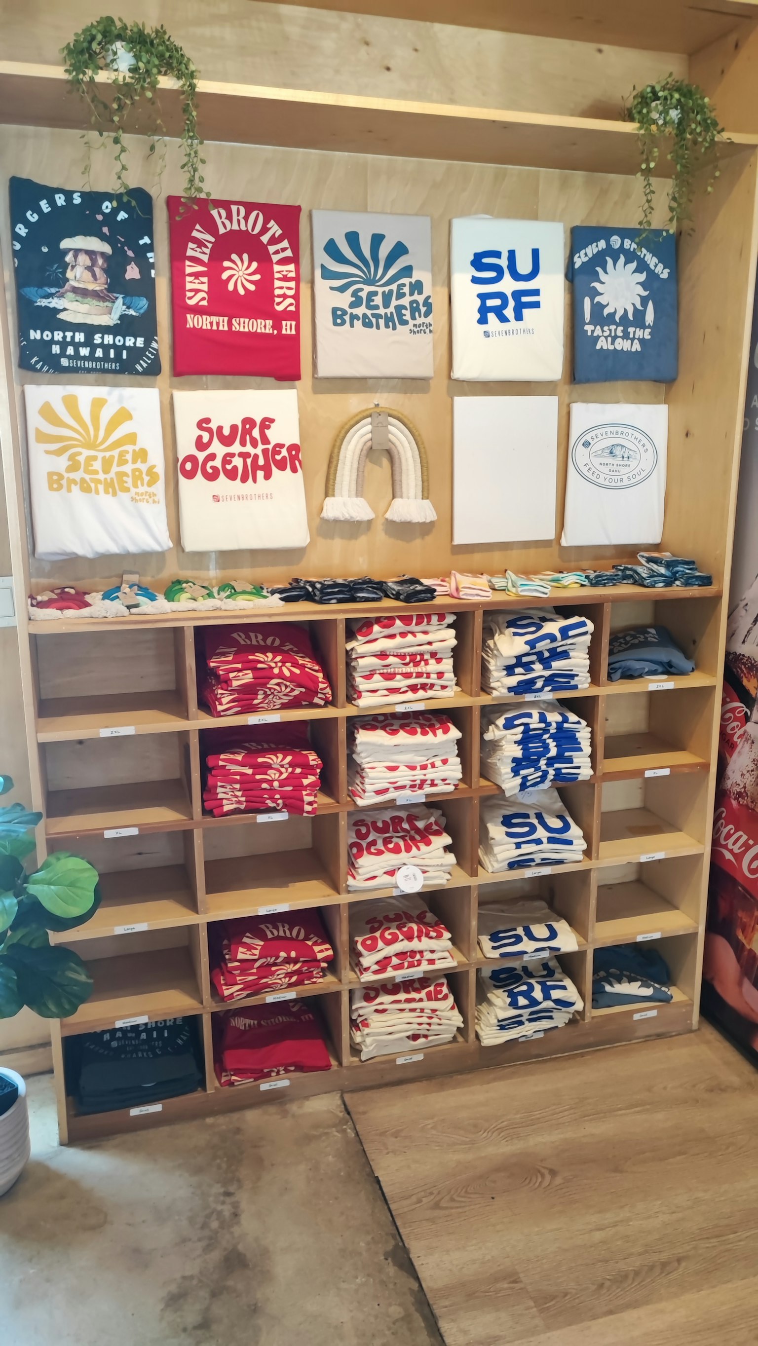 Holzregal, das bunte T-Shirts mit verschiedenen Druckdesigns darüber zeigt