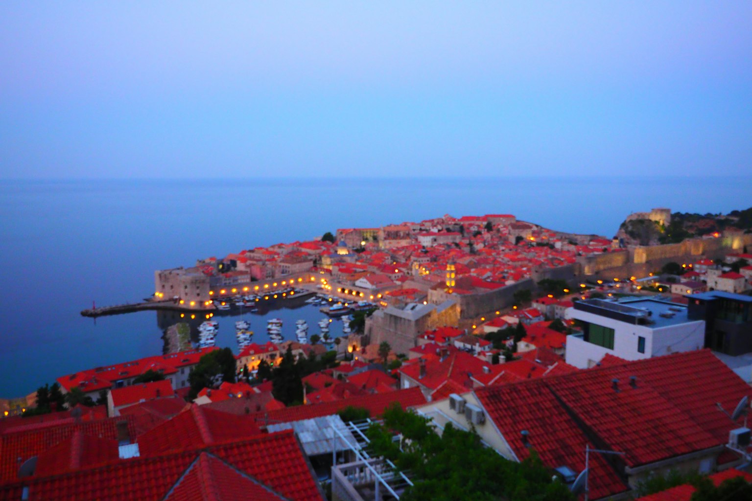 Pemandangan indah pantai Dubrovnik dengan rumah atap merah di bawah langit biru saat senja