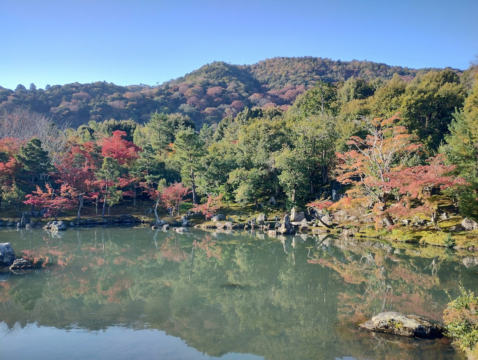 Serene pond surrounded by vibrant autumn foliage and hills