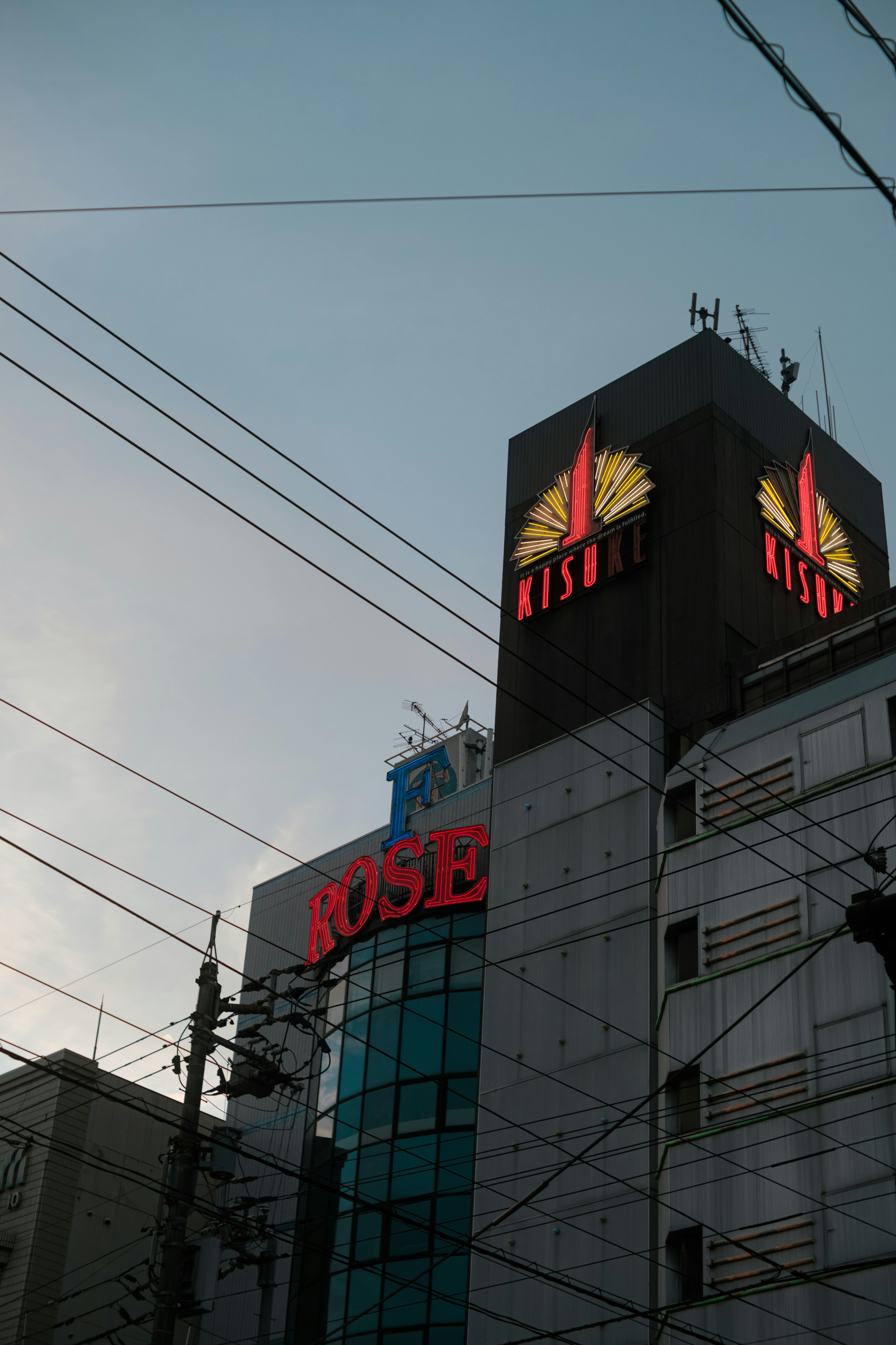 電線と看板が重なる街のビル外観
