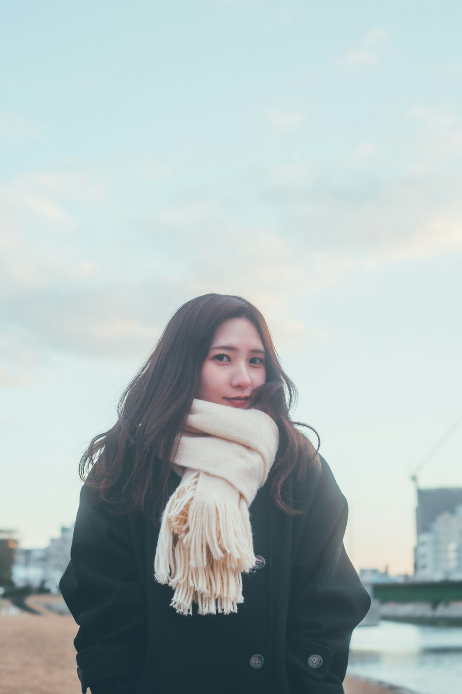 一位女性站在風景中，佩戴白色圍巾
