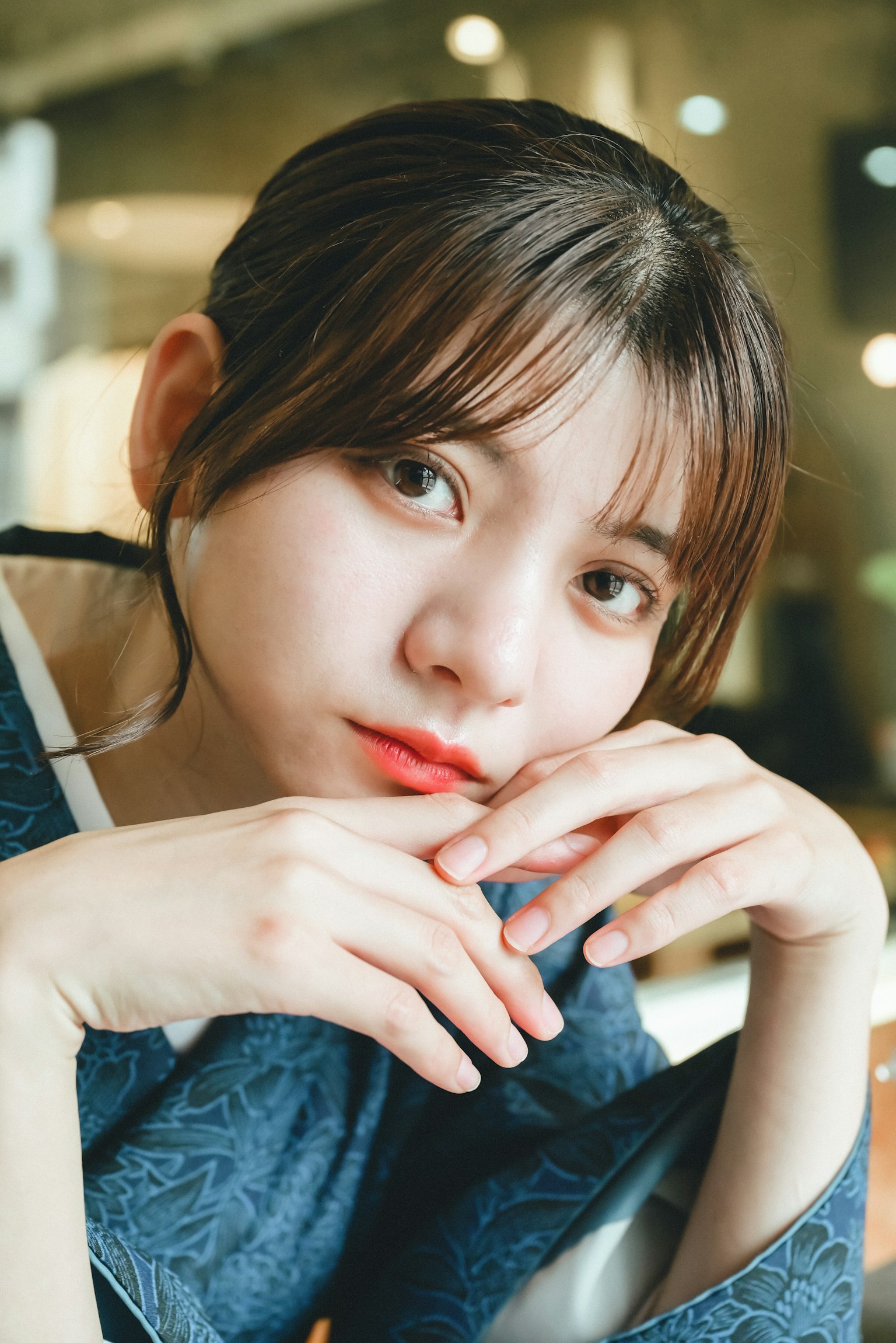 年輕女性雙手交疊，沉思地看著