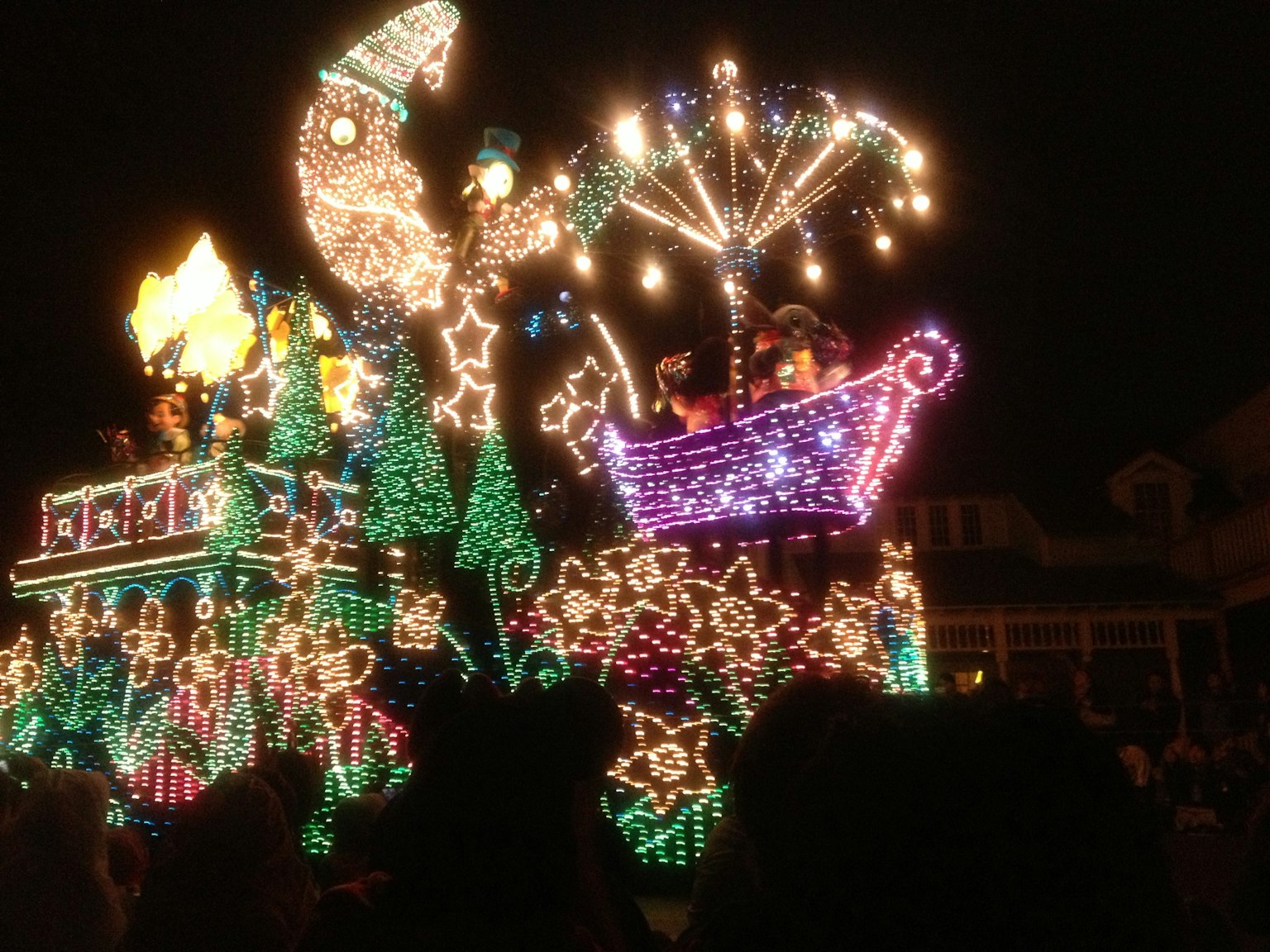 Colorful illuminated parade float featuring a whimsical design with stars and a large umbrella