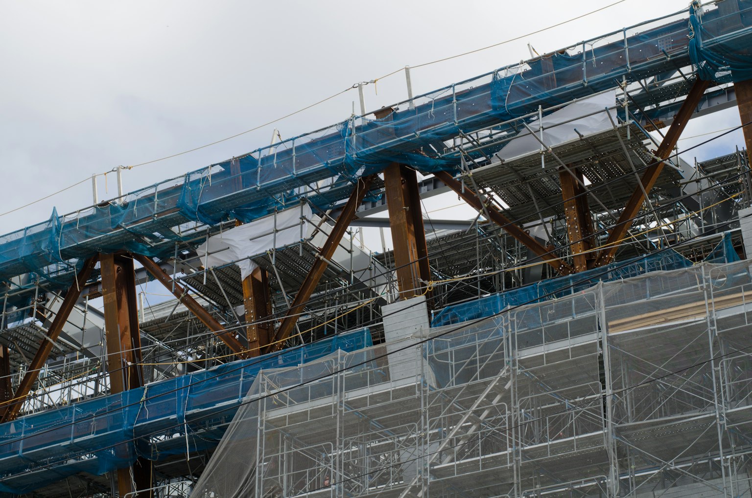 Primo piano di un cantiere che mostra impalcature blu e travi di legno