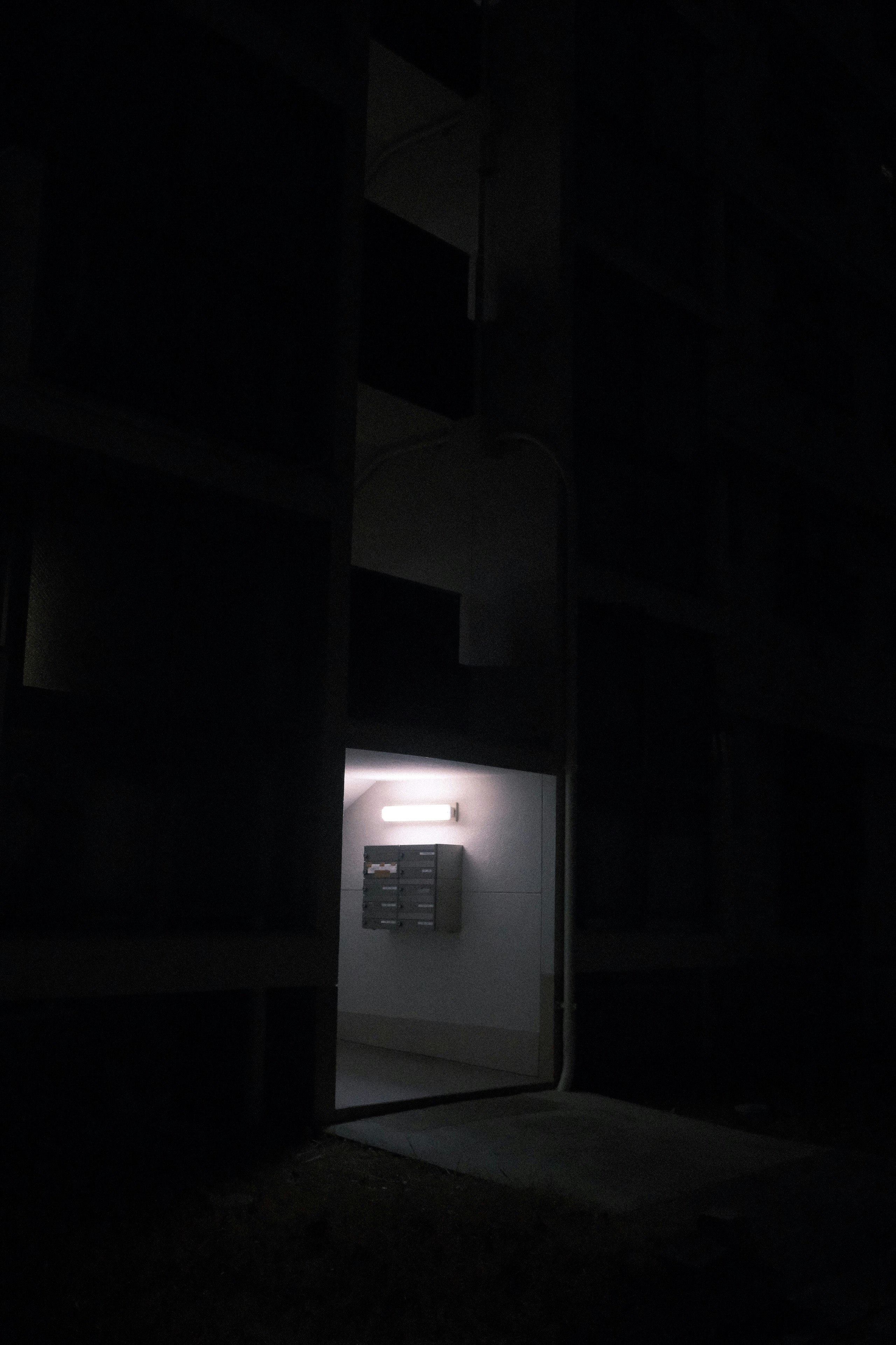 暗い路地の奥に灯る小さな看板と玄関口