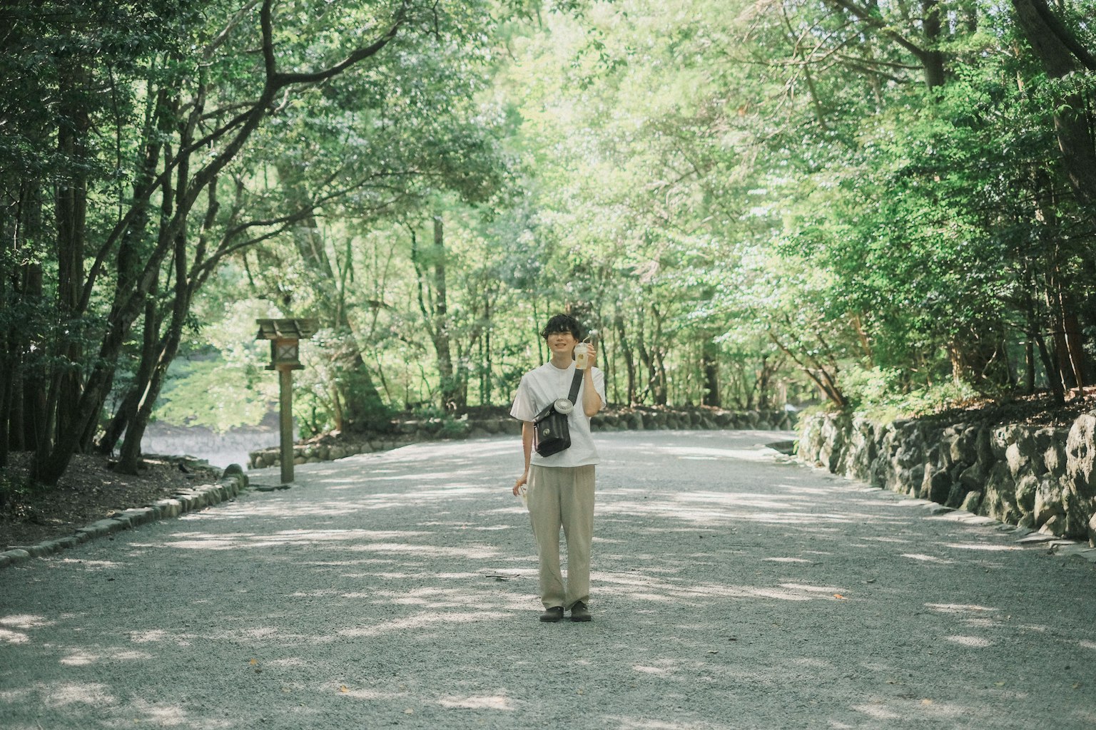 A man standing in a lush green forest with sunlight filtering through the trees